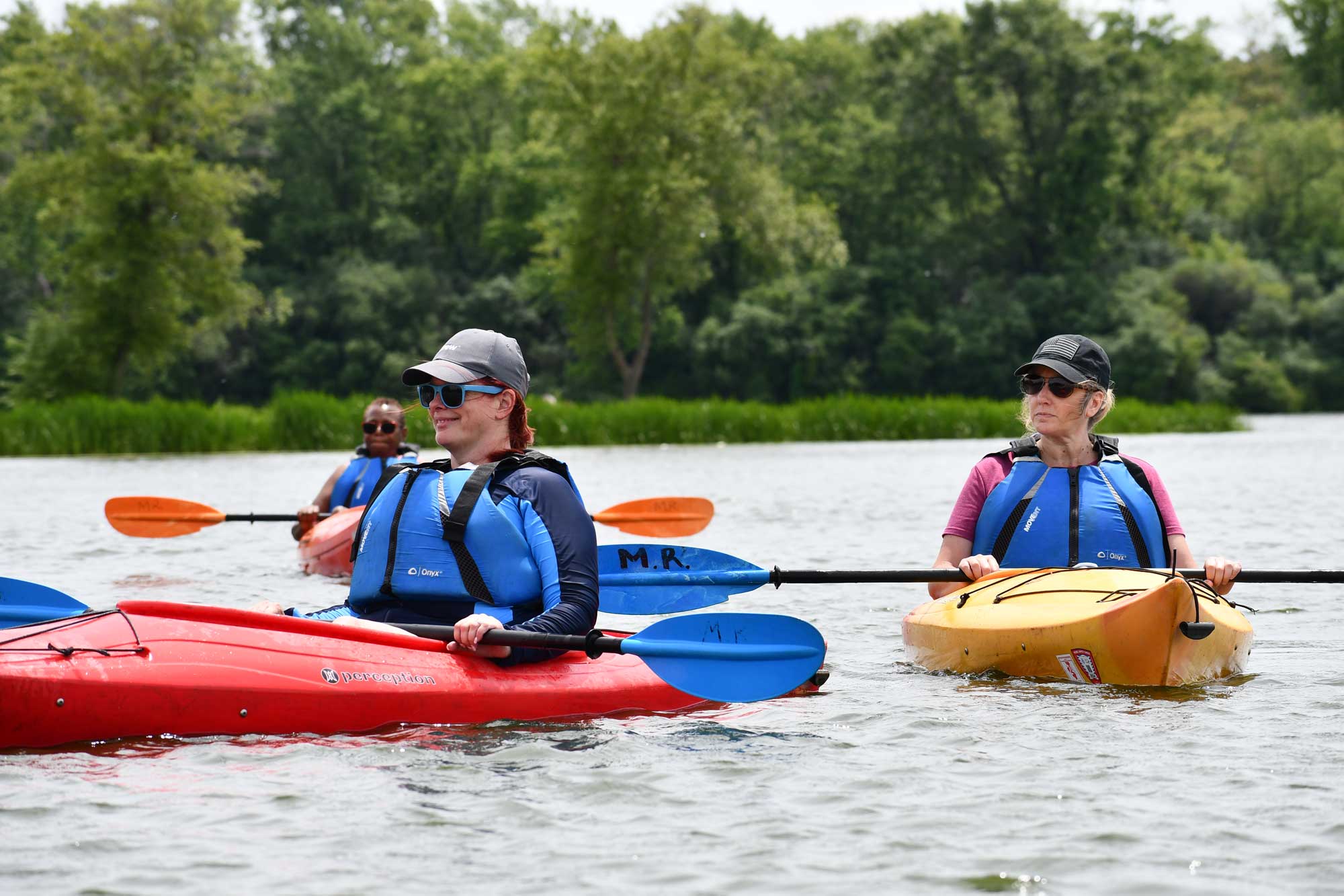 People kayaking in a reservoir with trees in the background.