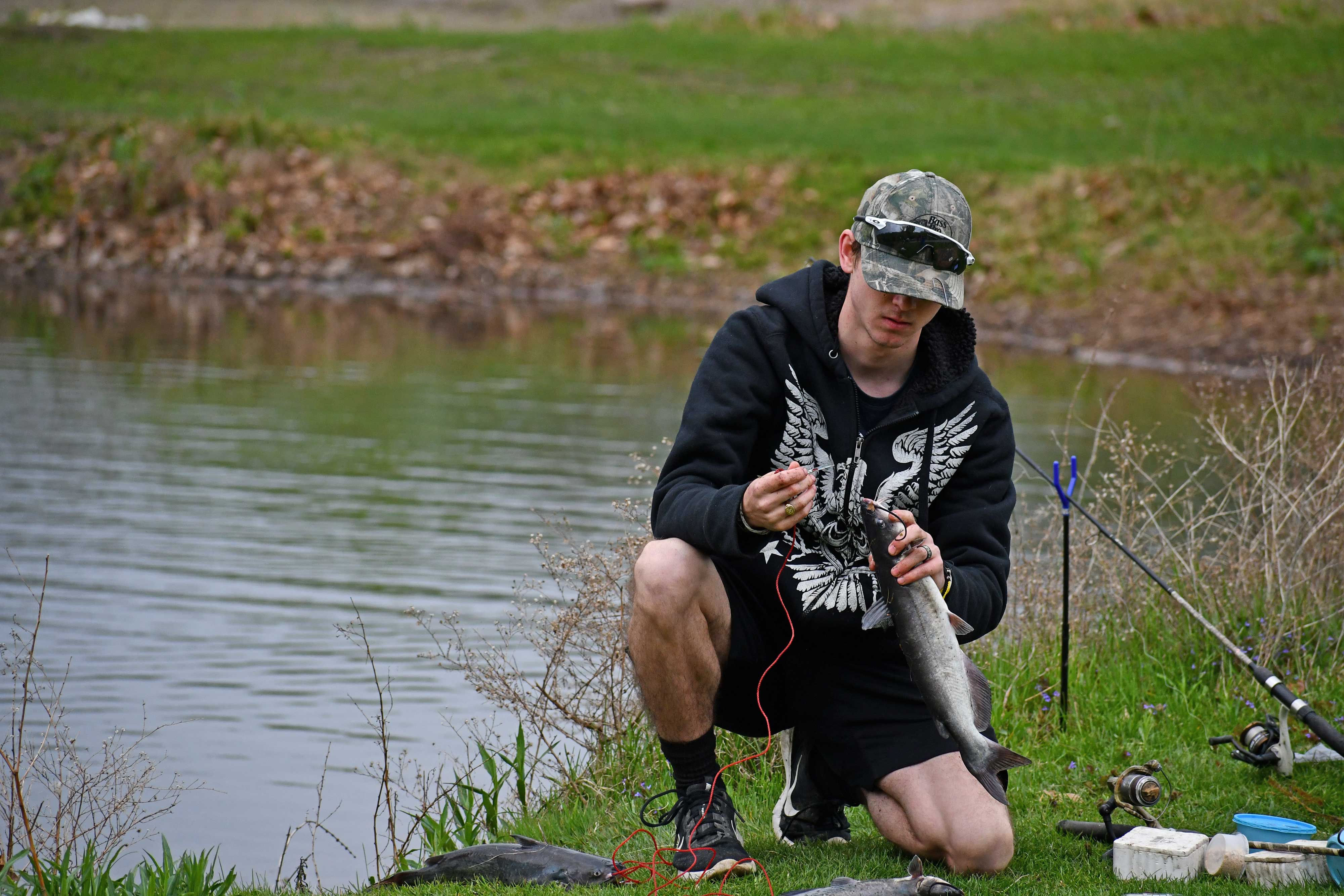 A man takes a fish off his line.