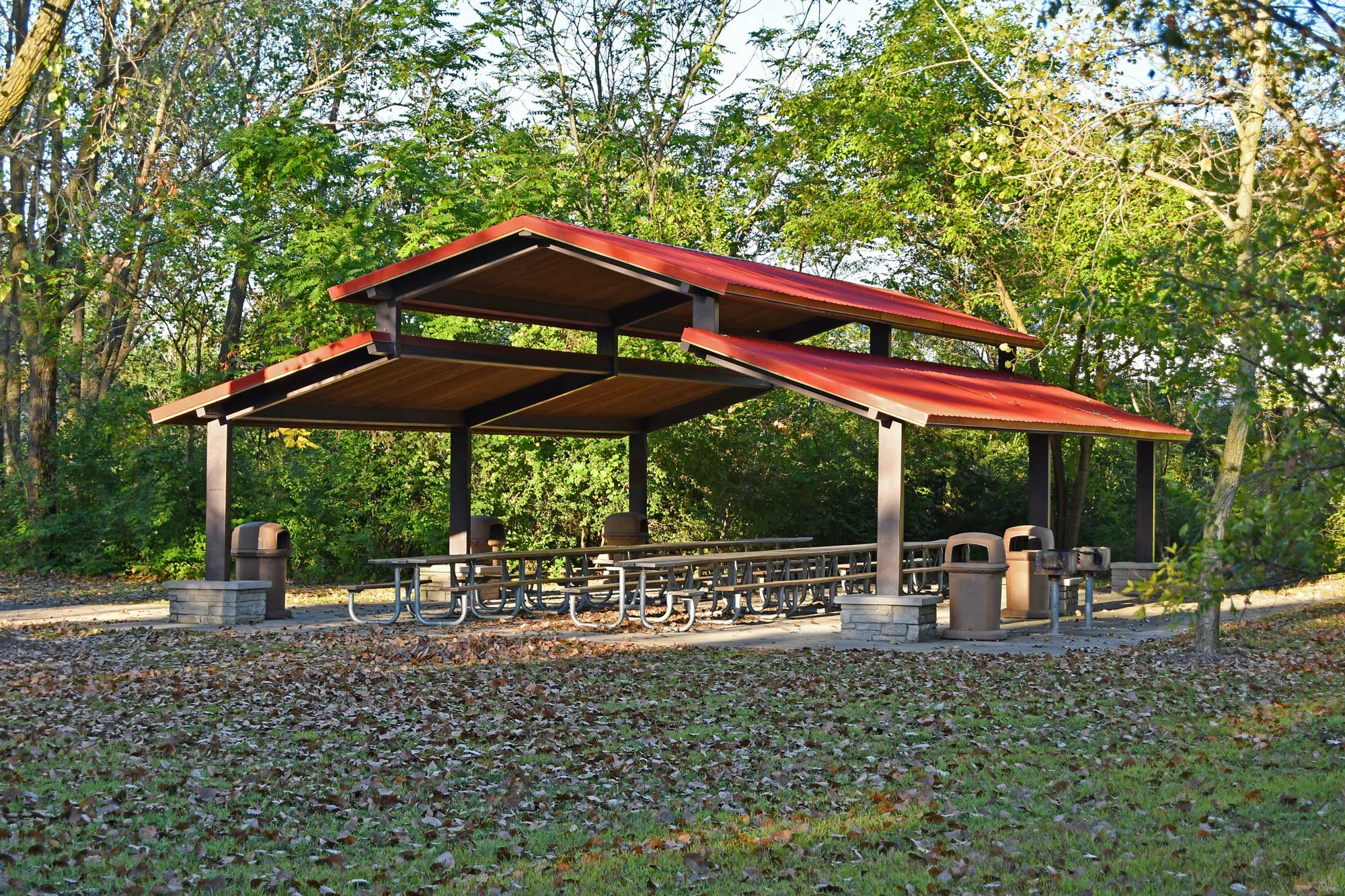 A picnic shelter surrounded by tall trees at the end of a trail.