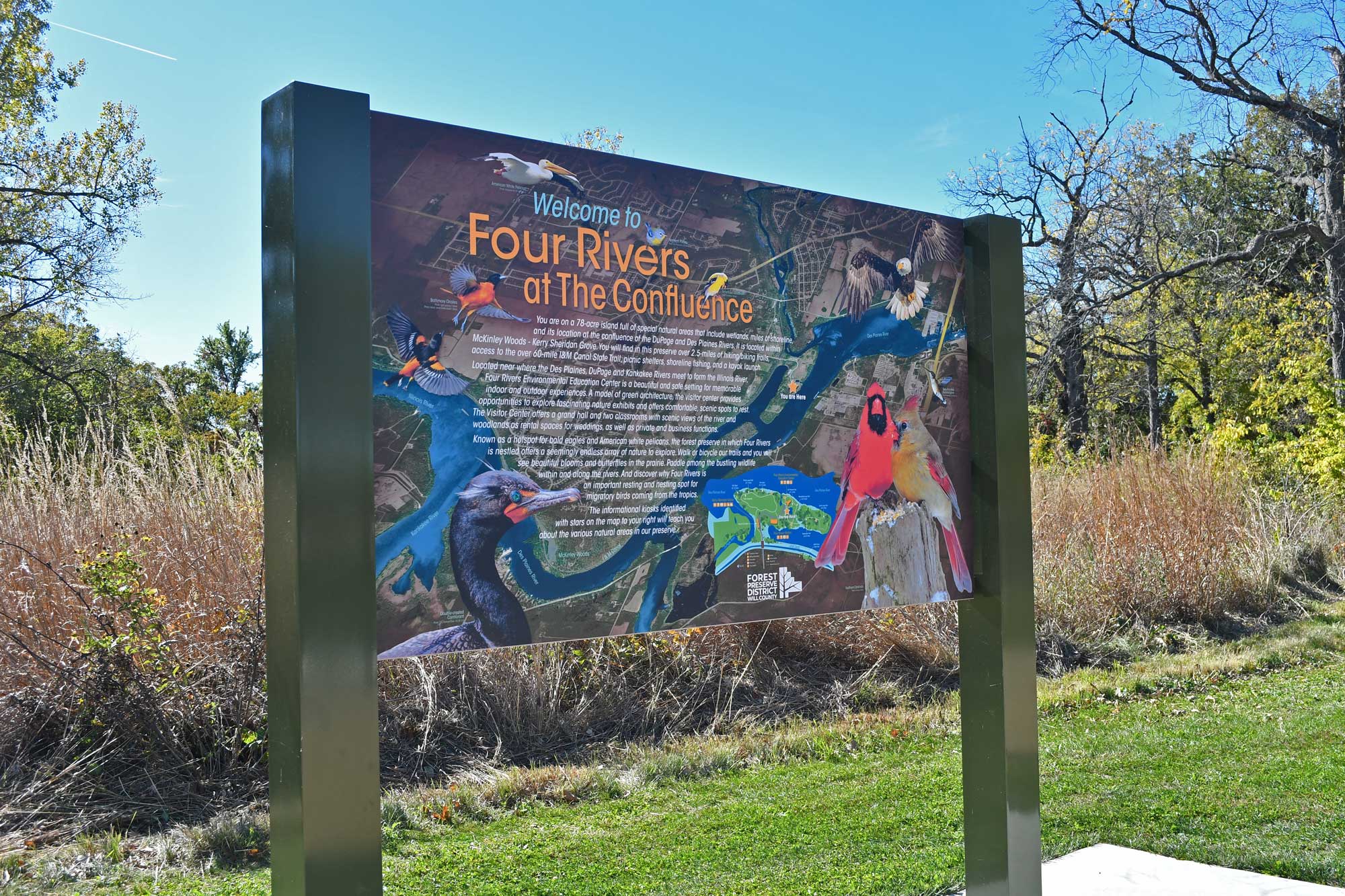 Trail signage with vegetation and trees in the background.