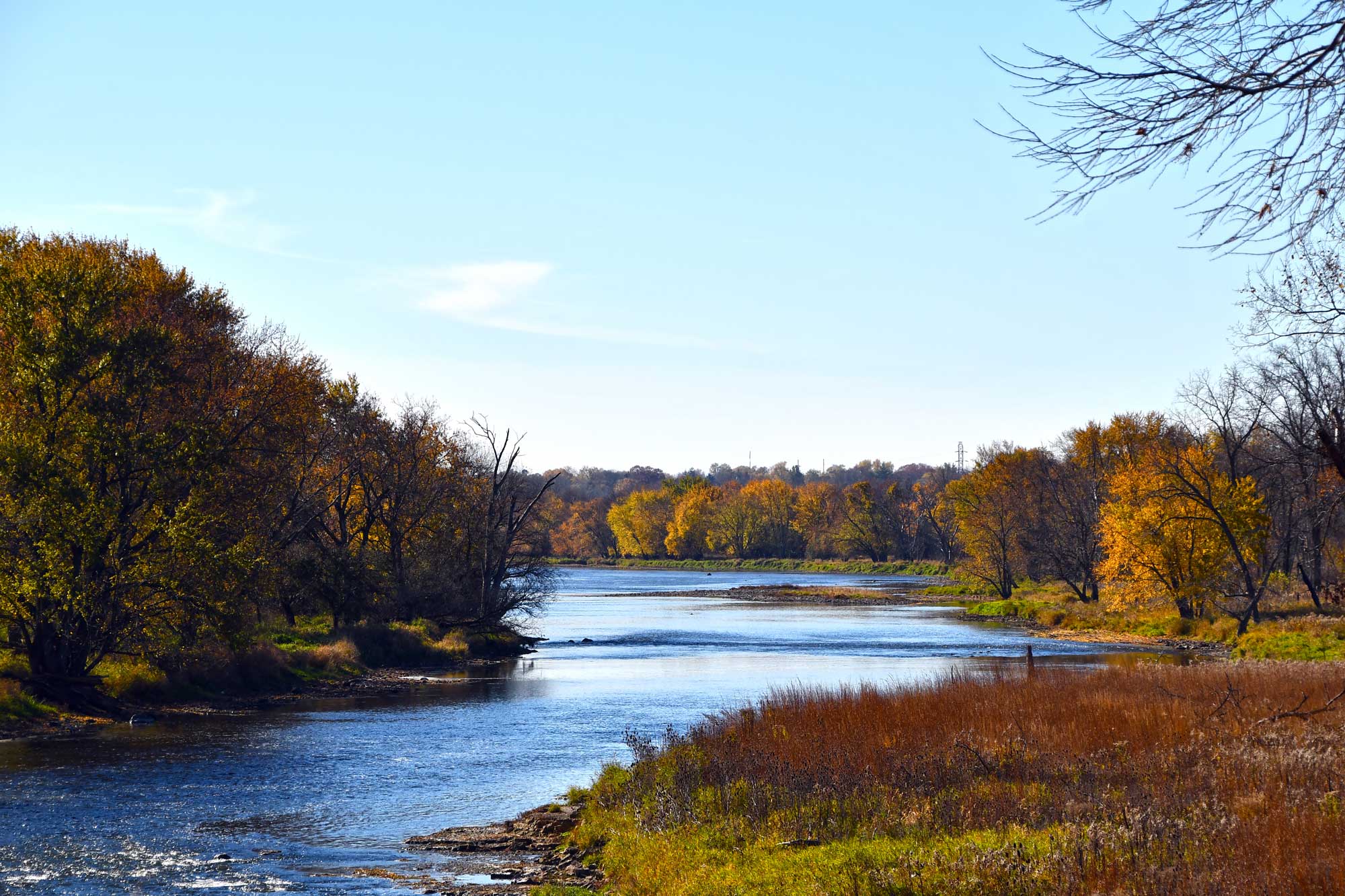 River lined by prairie and fall colored trees.