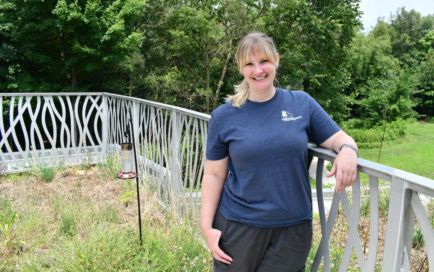 A woman standing on a roof deck overlooking a forest.