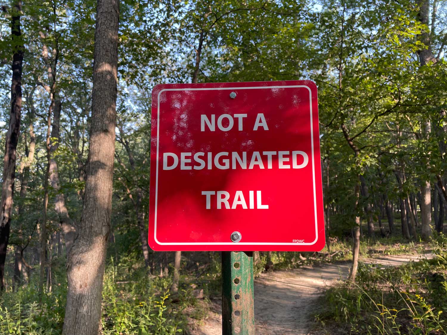 A sign designating a trail closure posted at the head of a trail.