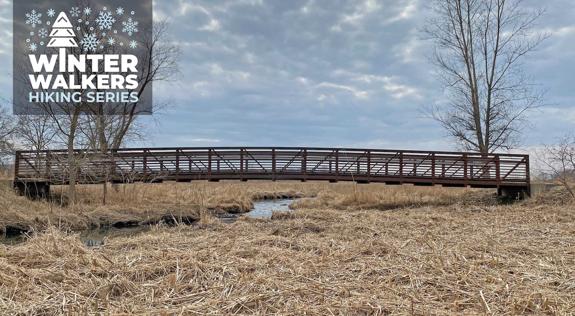 A bridge spanning a creek in a winter landscape.