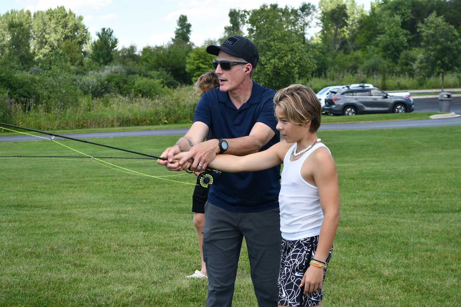 An adult showing a child how to cast a fishing pole.