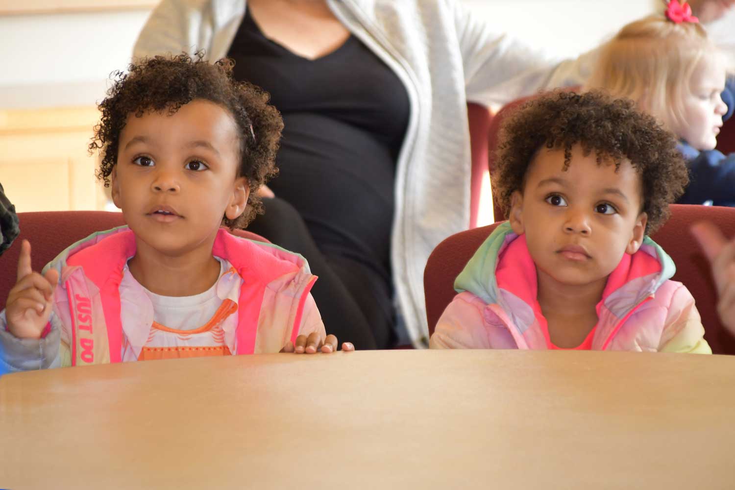 Two young children sitting attentively at a table.