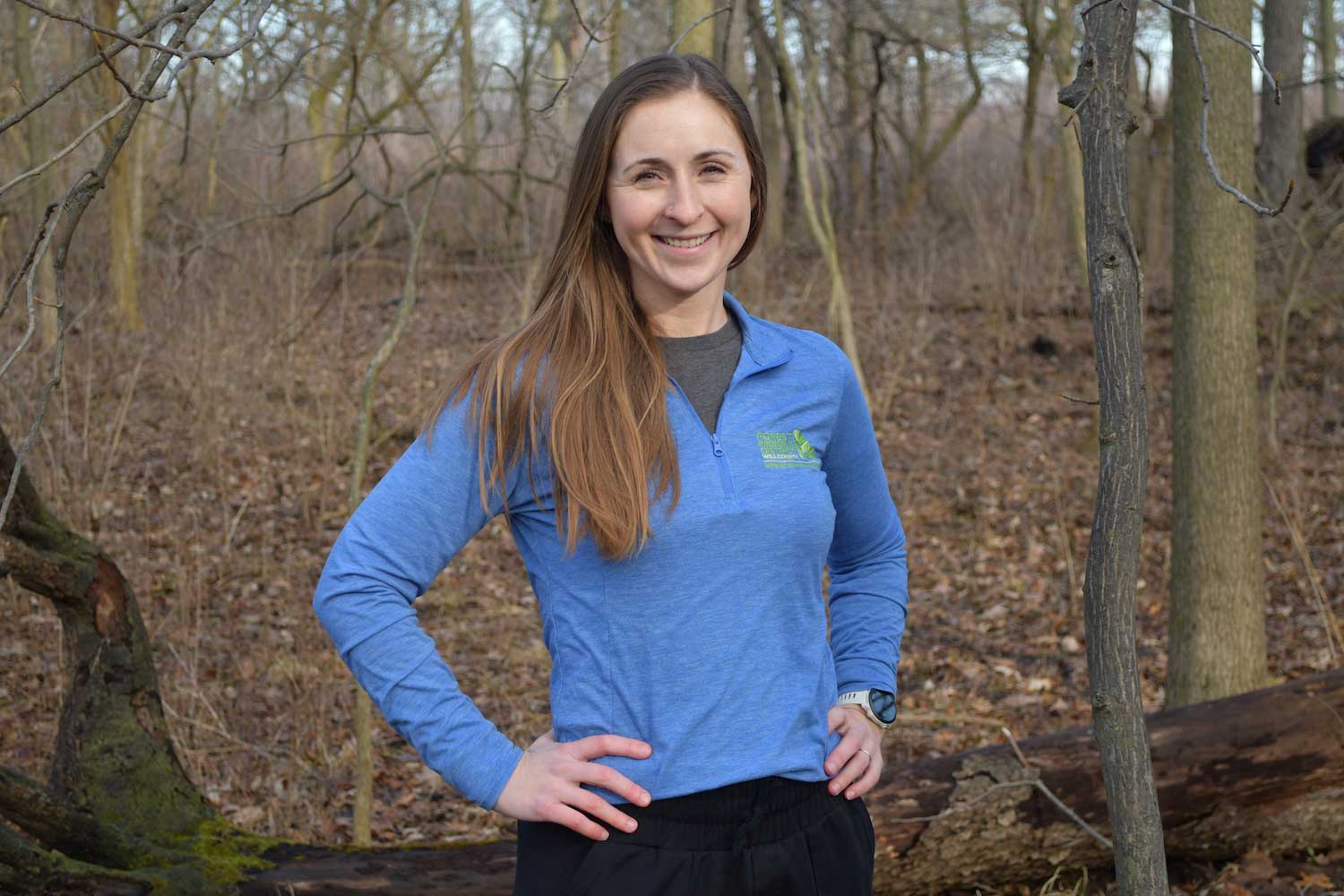 A person standing in front of a forest.