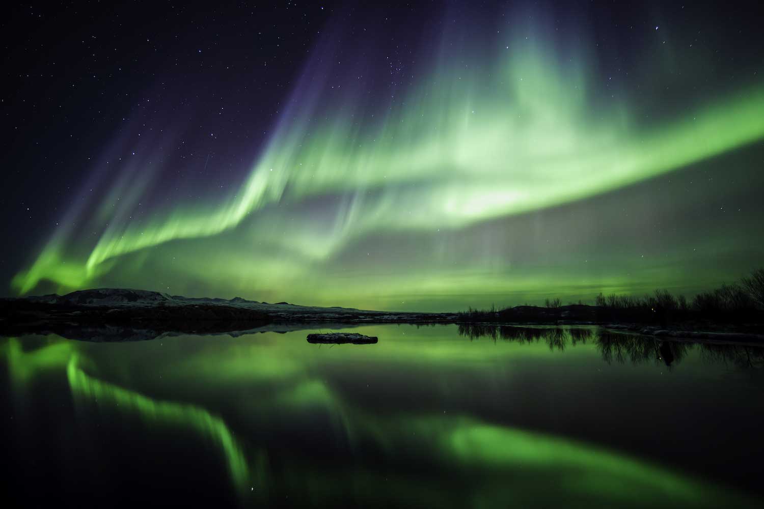 The green glow of the northern lights in the night sky.