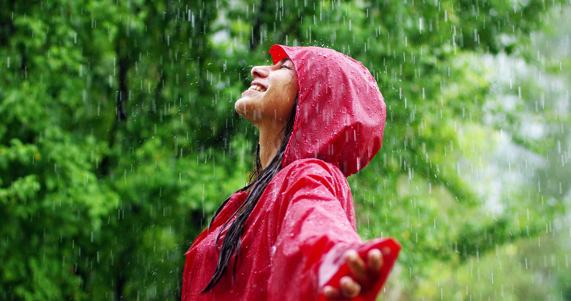 A woman in a raincoat standing in the rain.