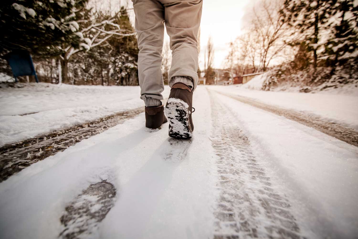 A person wearing boots walking on a snowy trail.