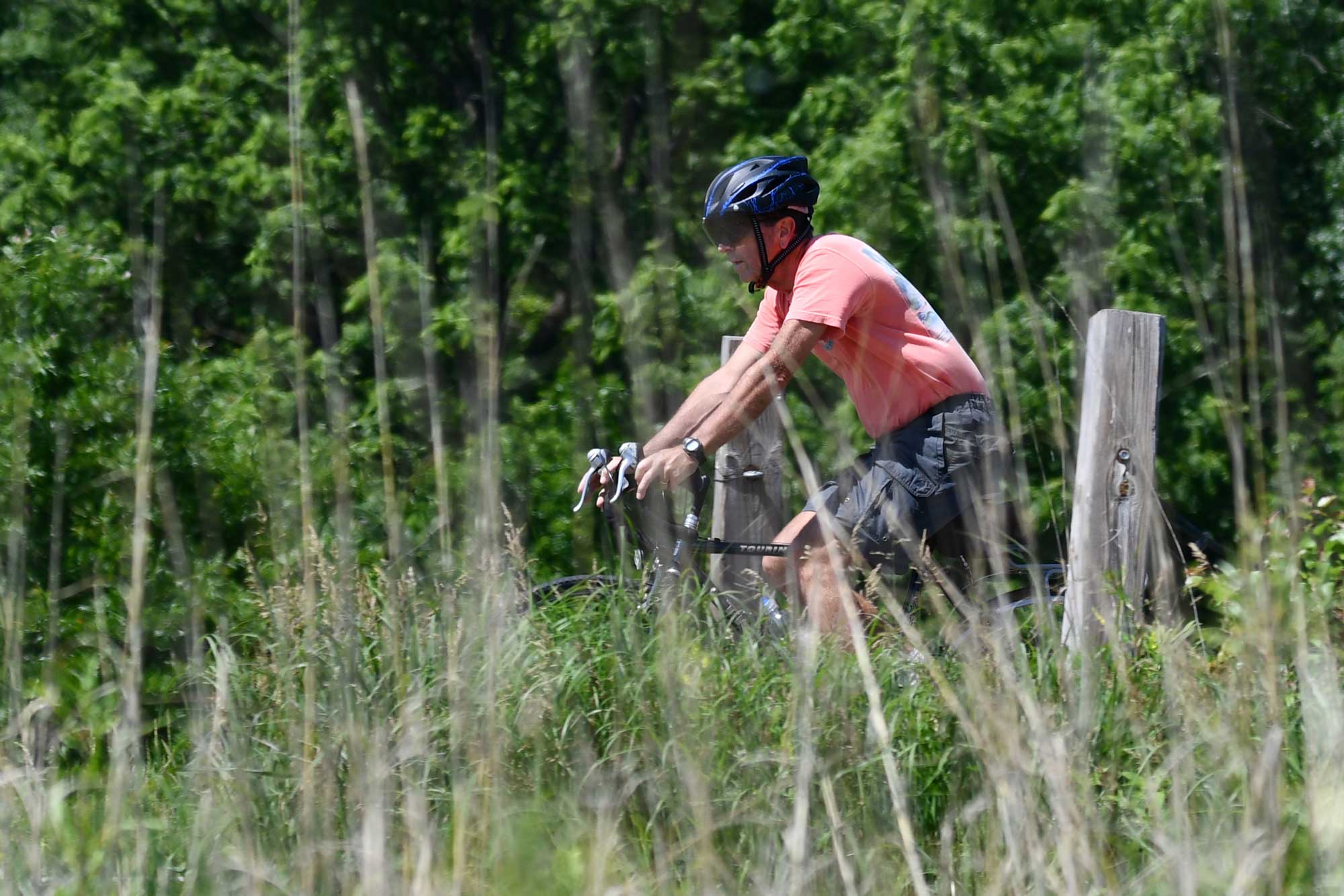 A man wearing a helmet rides his bike on a trail.