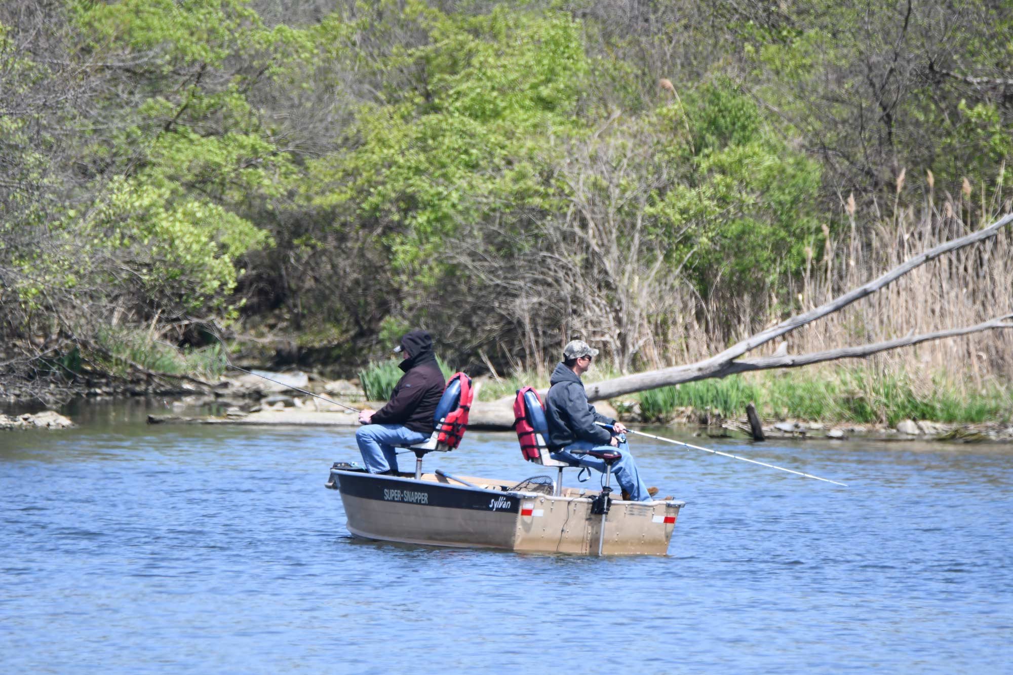 Two men fish on a boat.