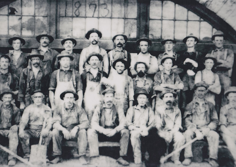 A historical photo of workers at a Joliet manufacturing facility.