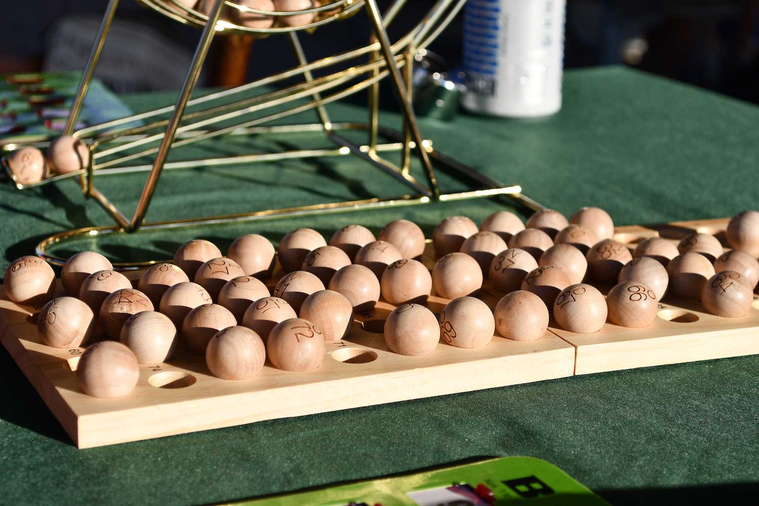 Wooden bingo balls and a bingo ball holder on a table.