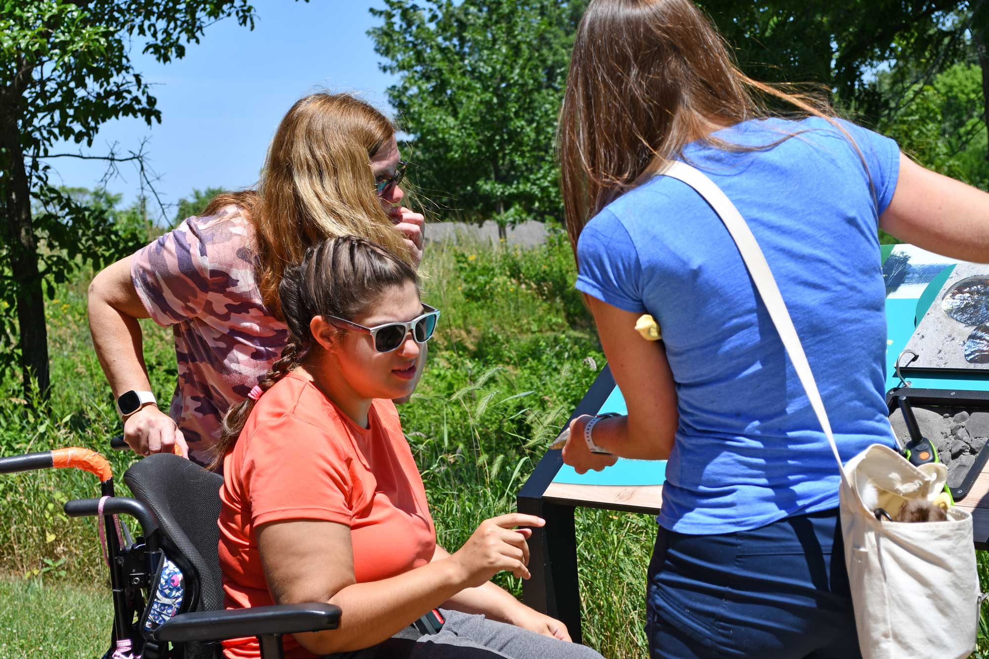 A woman in a wheelchair looks at an interpretive sign.