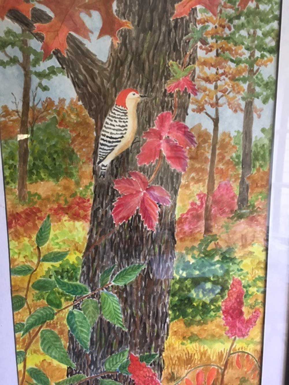 A painting of a red-bellied woodpecker on a tree trunk with fall-colored leaves surrounding it.