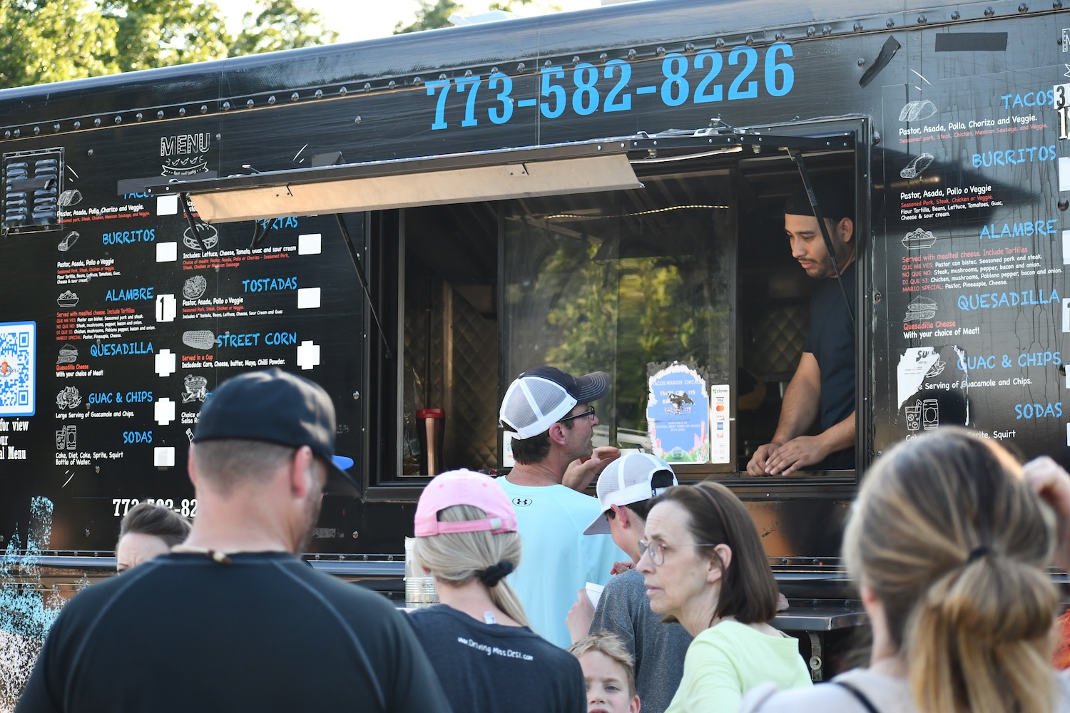 A line of people at the window of a food truck.