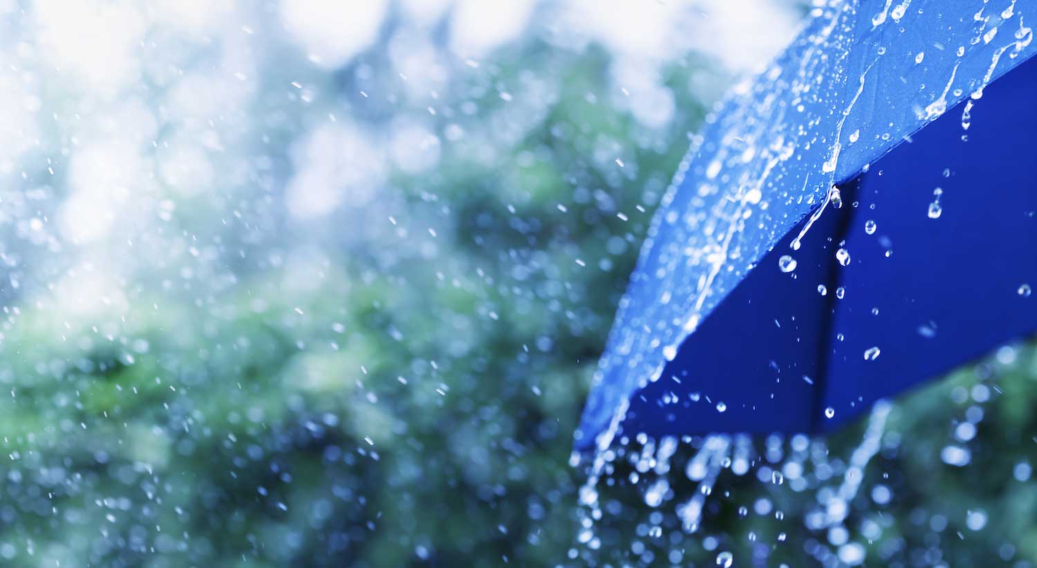 A blue umbrella with rain pouring off of it.