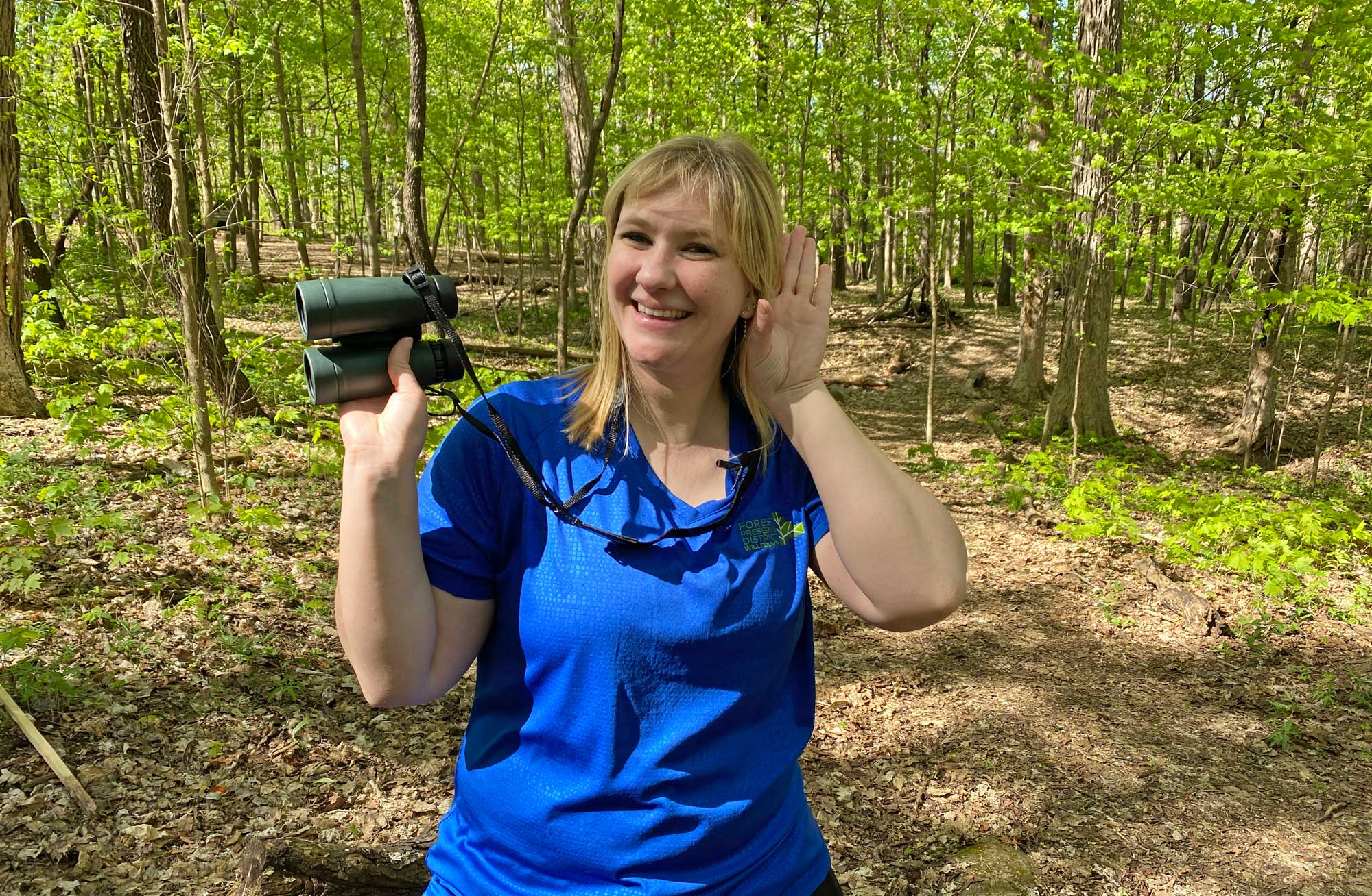 "The Buzz" host Suzy Lyttle stands in the woods while listening for birds. 