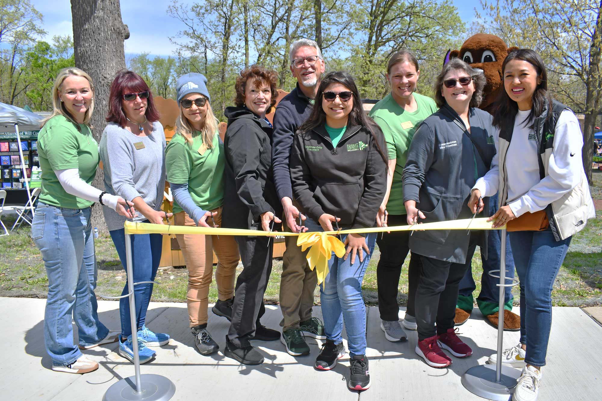 Men and women cut a yellow ribbon at a grand opening