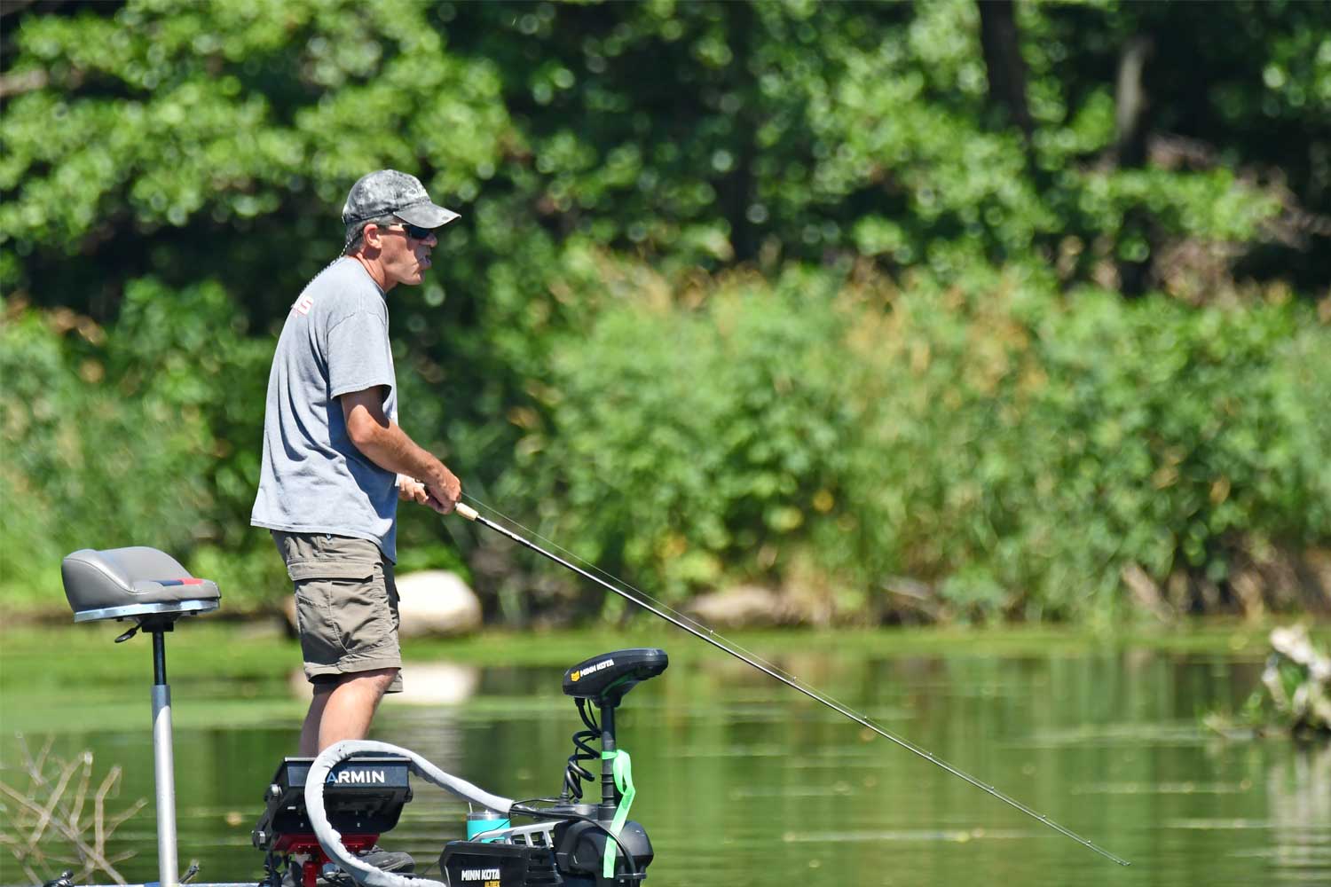 Person standing up in a boat while fishing.