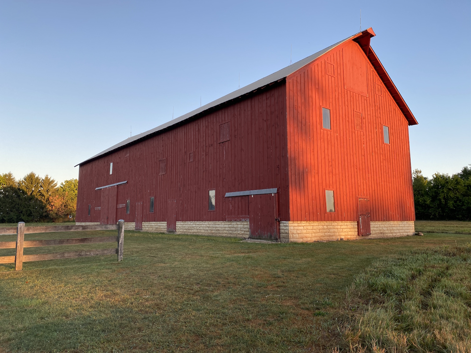 A large red barn in the light of the setting sun.