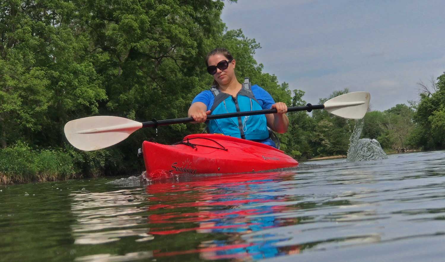 A person paddling a red kayak through the water.