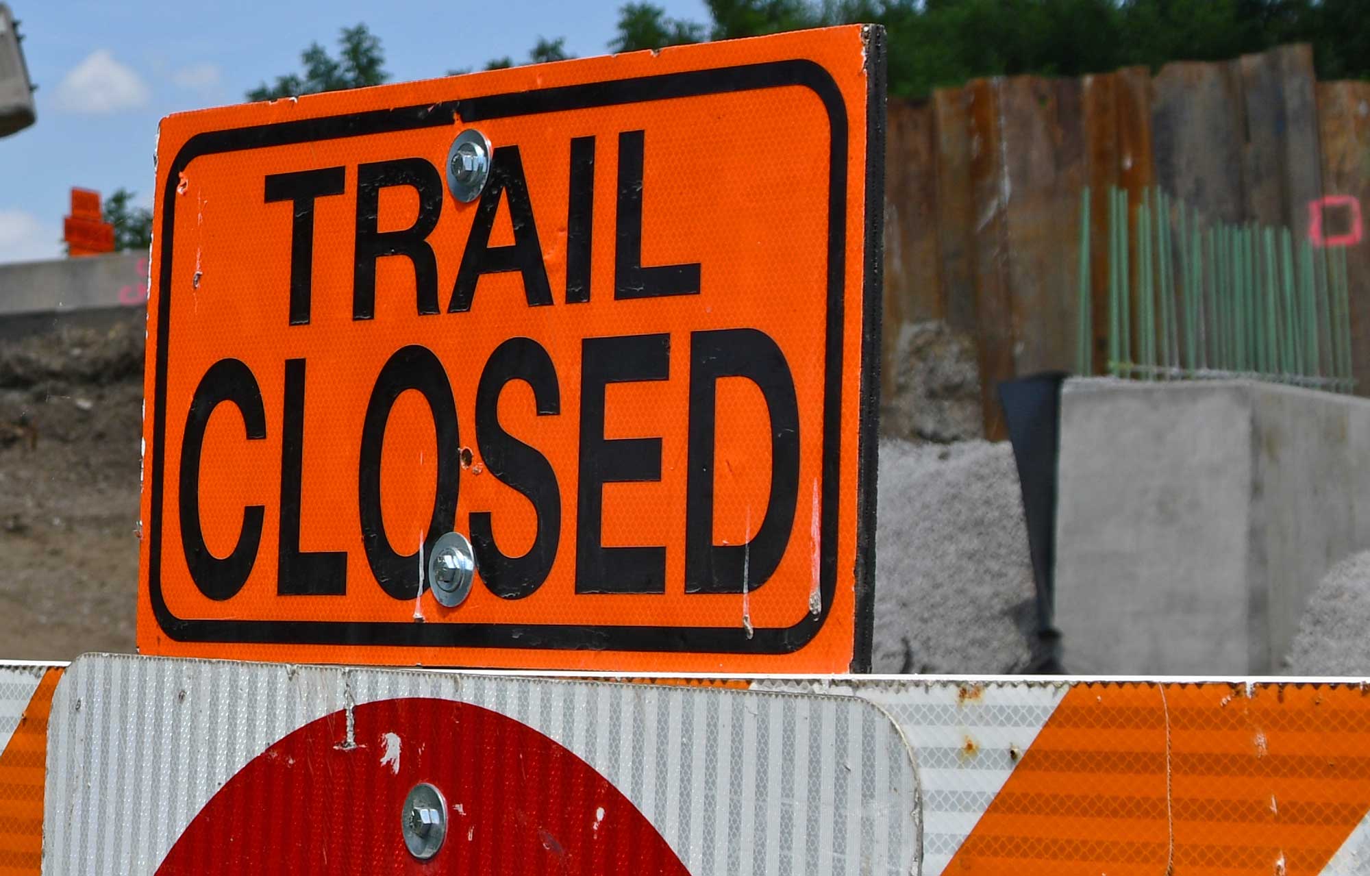 An orange sign showing a trail closed sign. 