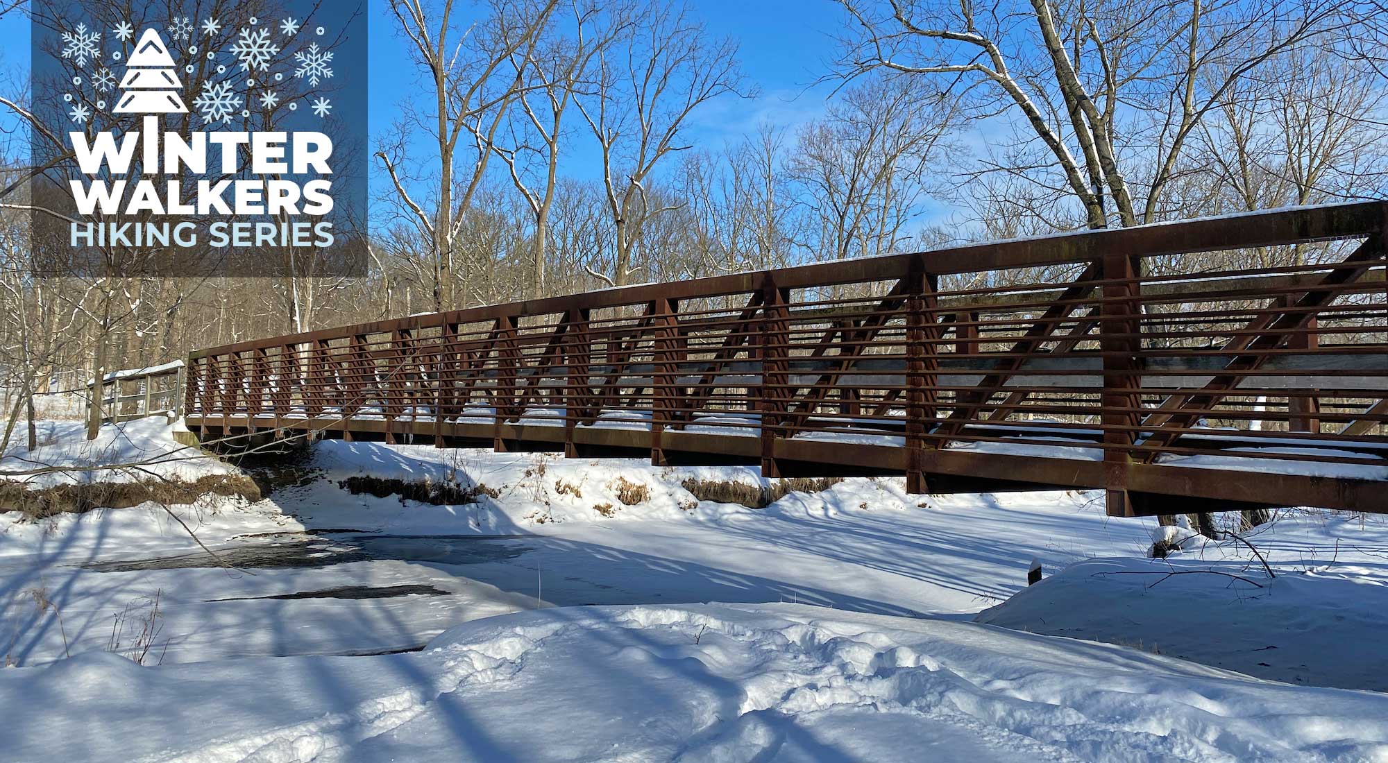 A wooden bridge over a snow-covered frozen creek.