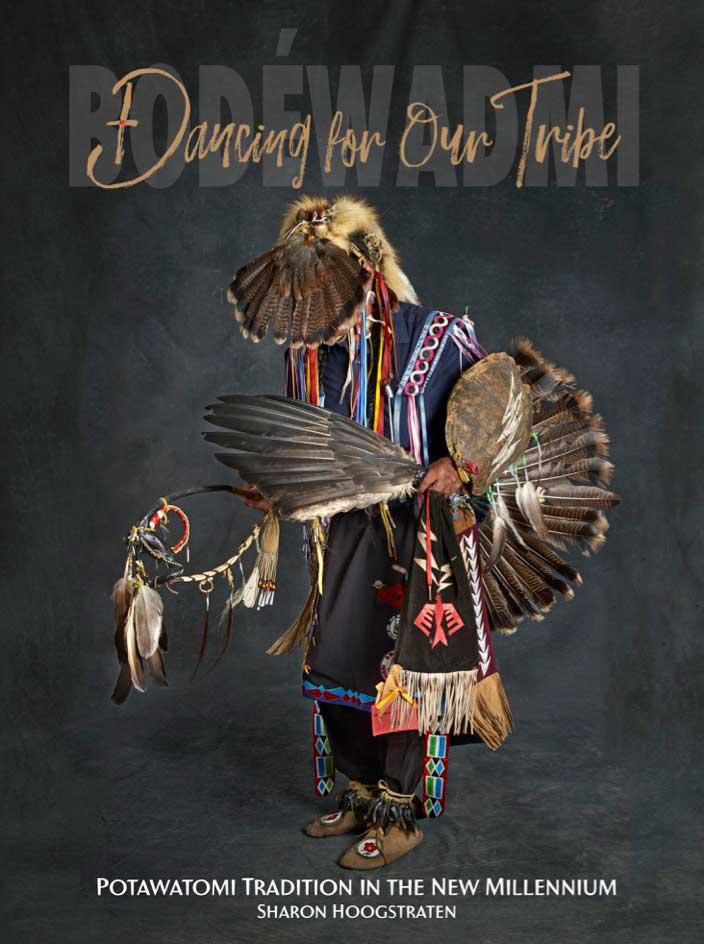 A person wearing traditional Potawatomi dress against a gray background.