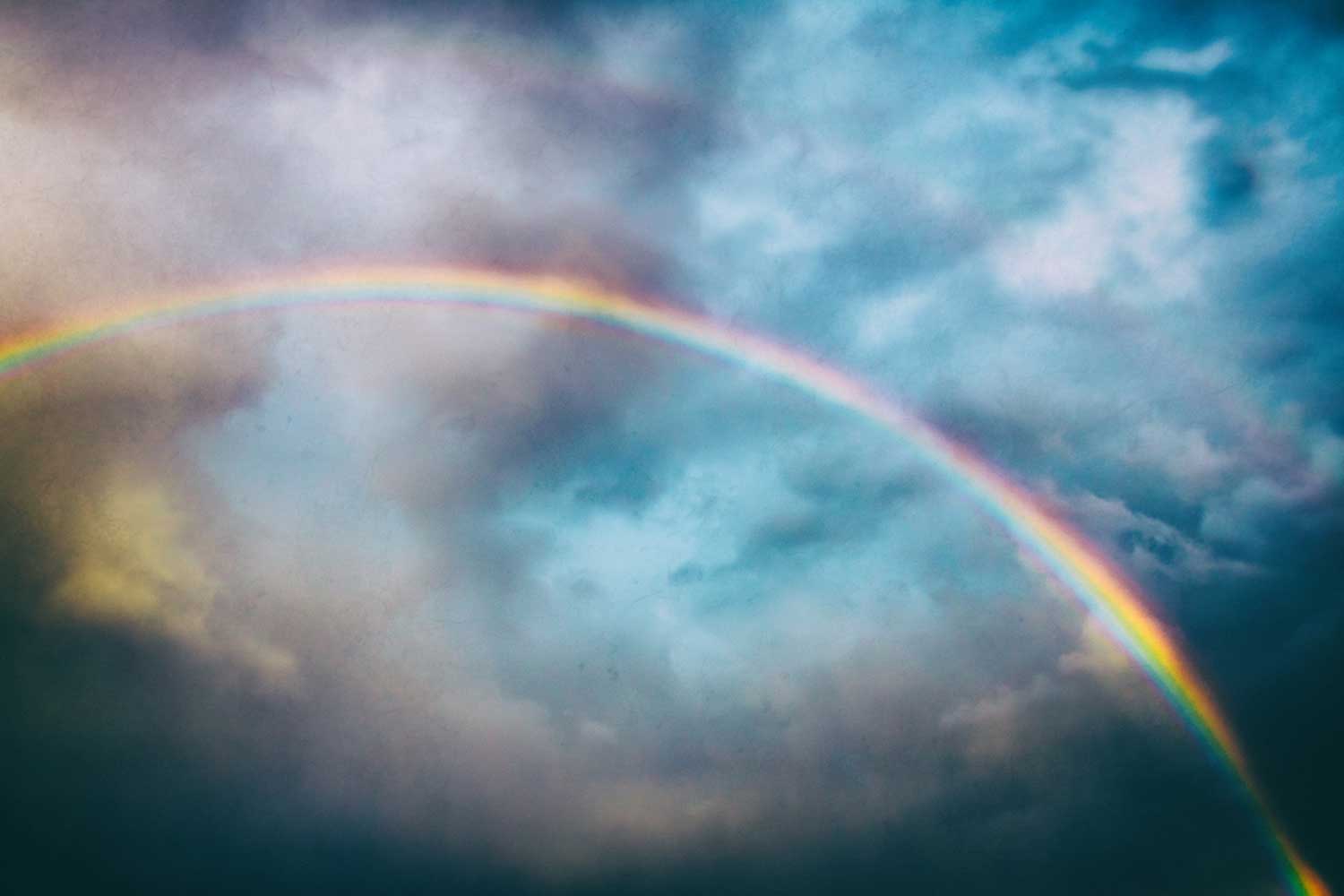 A rainbow in a partially cloudy sky.