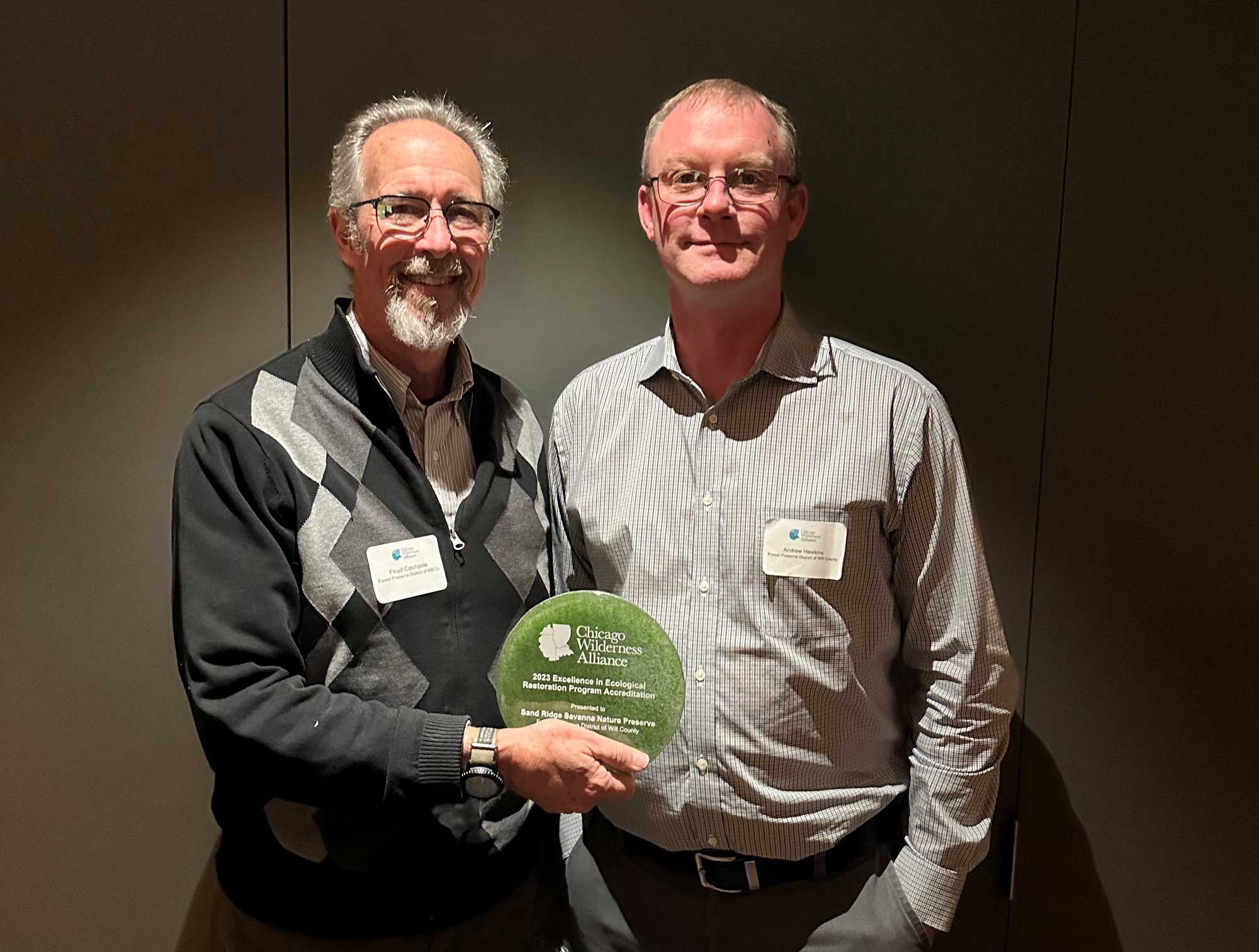 Two men hold an award.