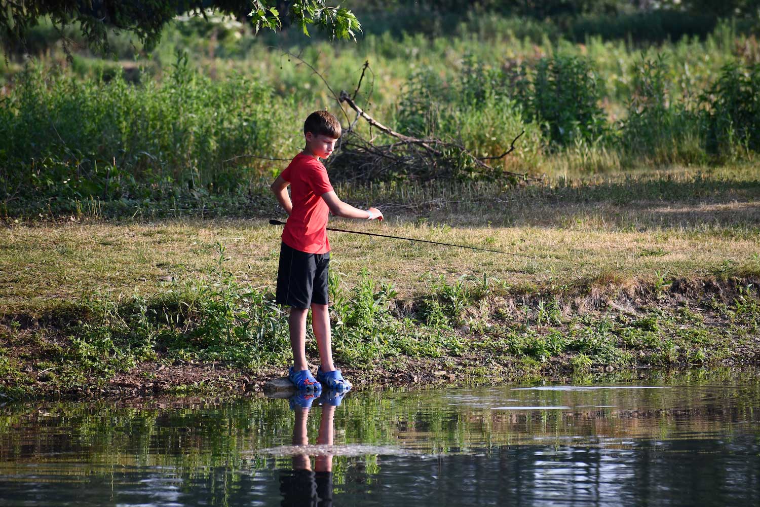 A child fishing along a shoreline.