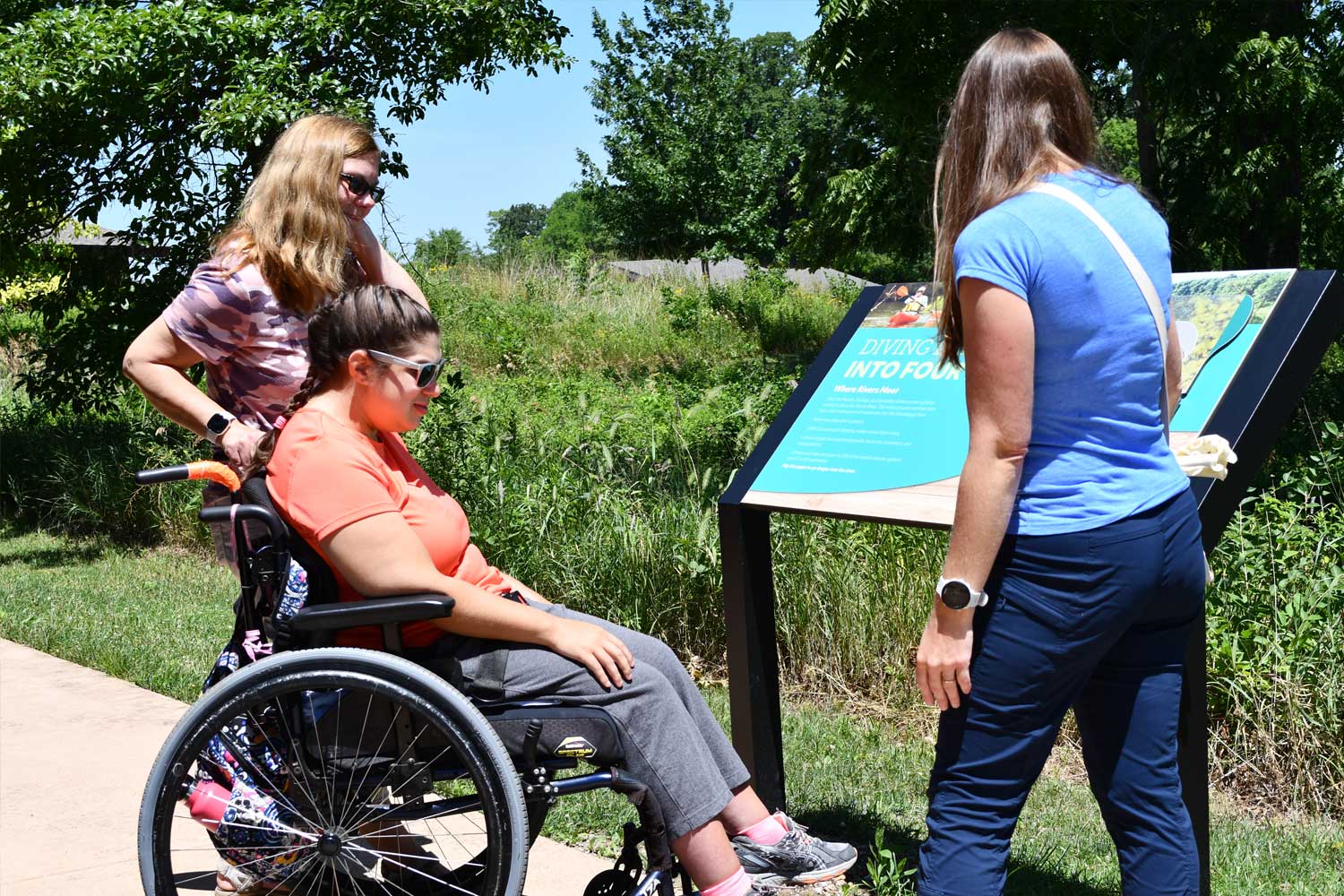 Woman in wheelchair taking a tour along a trail