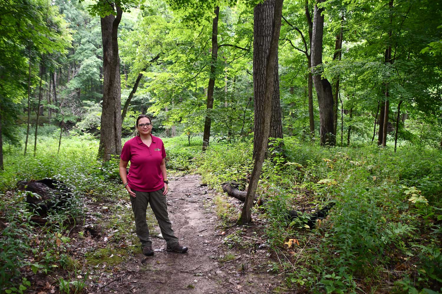 A person standing along a dirt trail in a forest.