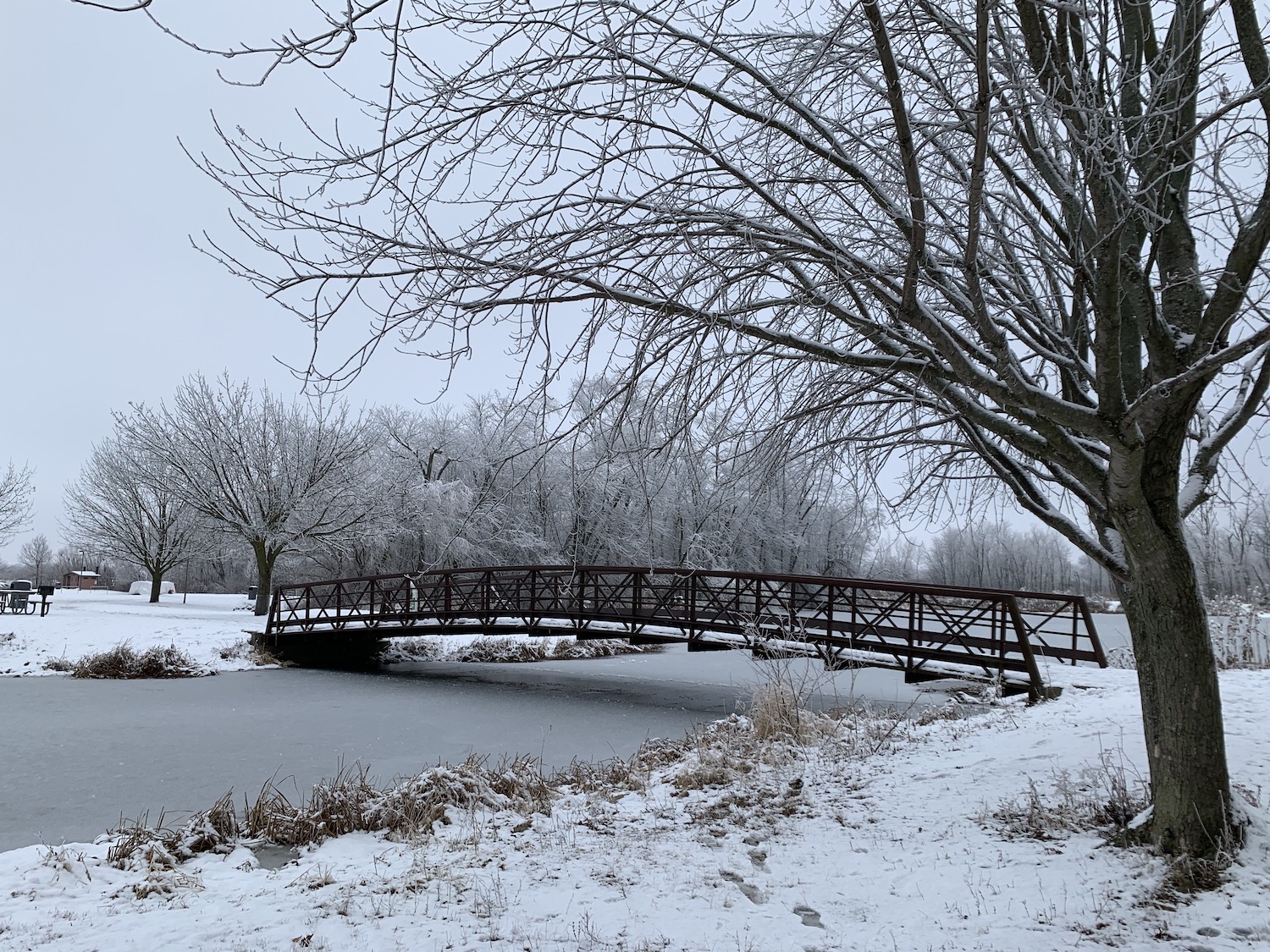 A snow-covered scene with a bridge over a waterway.