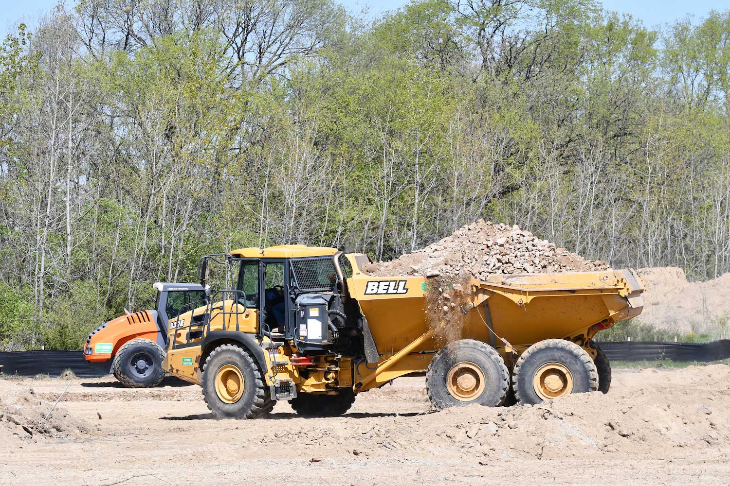 A dump truck hauling dirt driving through a construction zone.