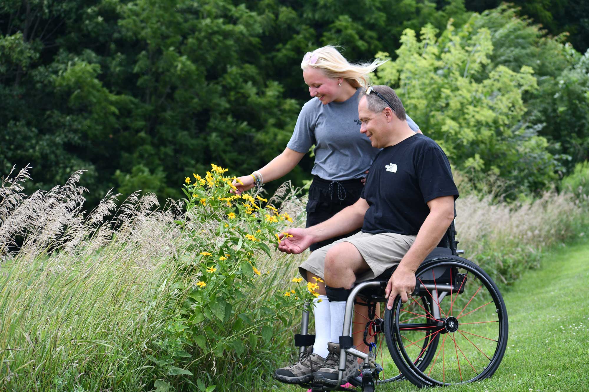 Man in wheelchair on trail with his daughter