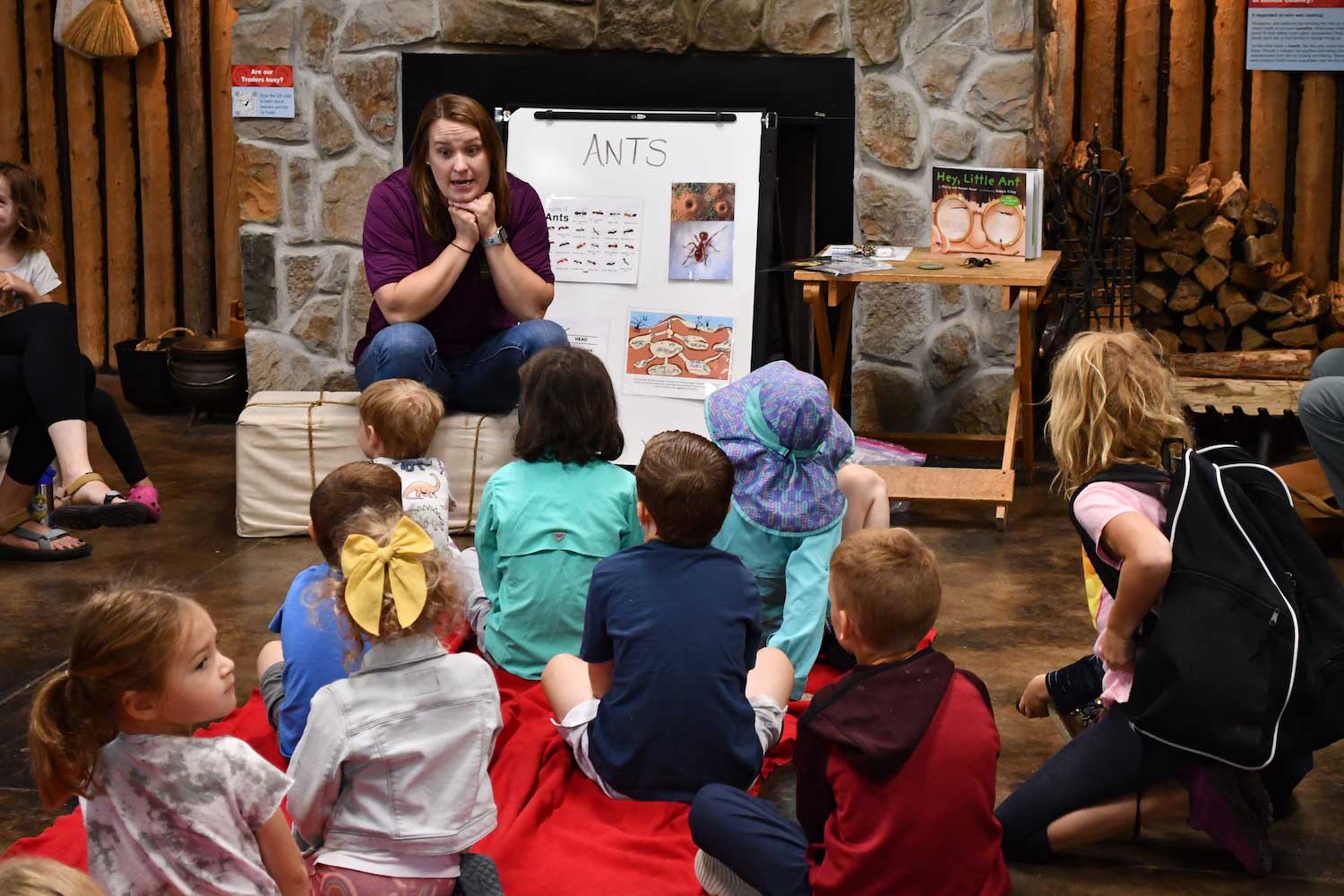 An adult talking to a group of kids sitting on the floor.