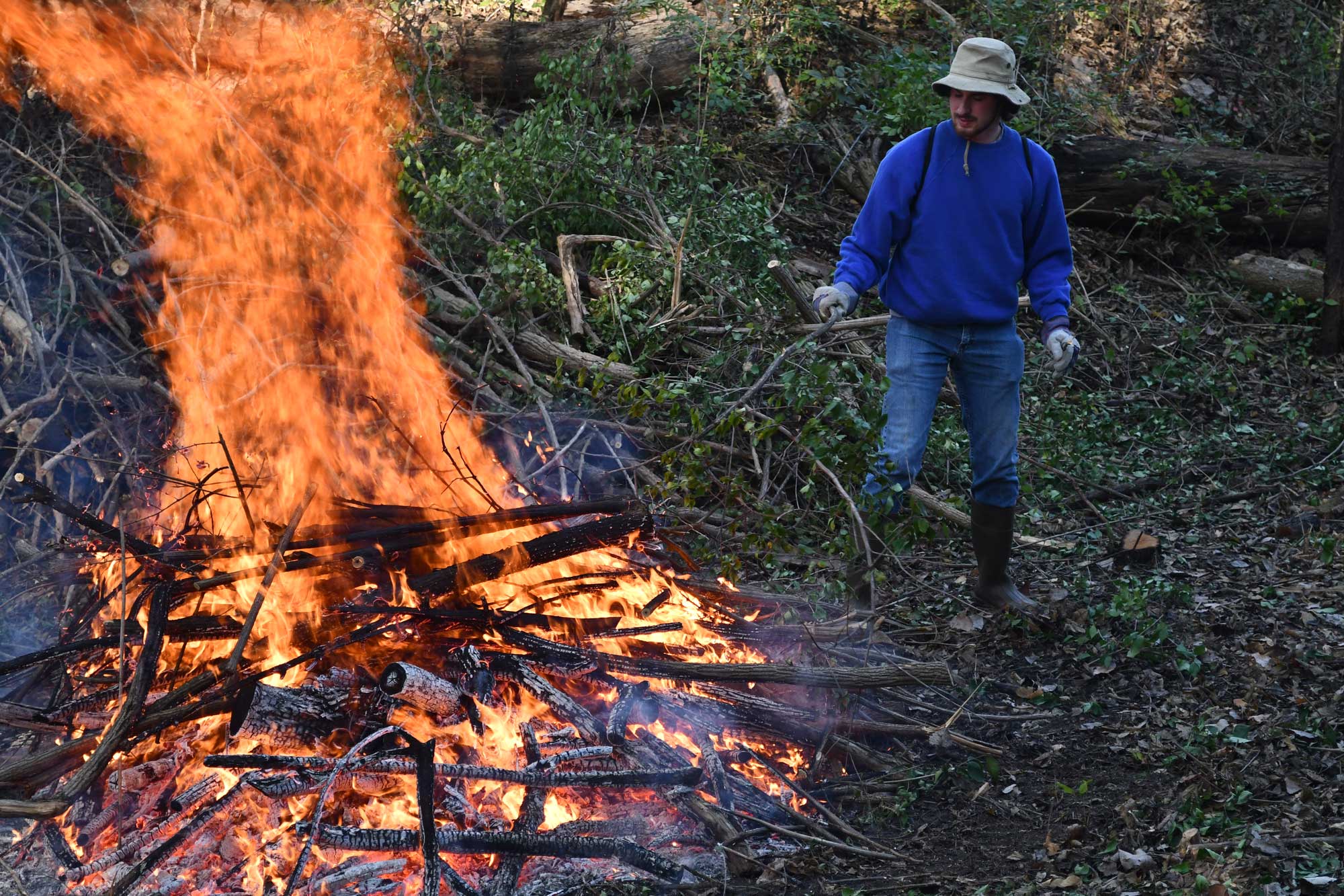 A man puts brush on a fire.