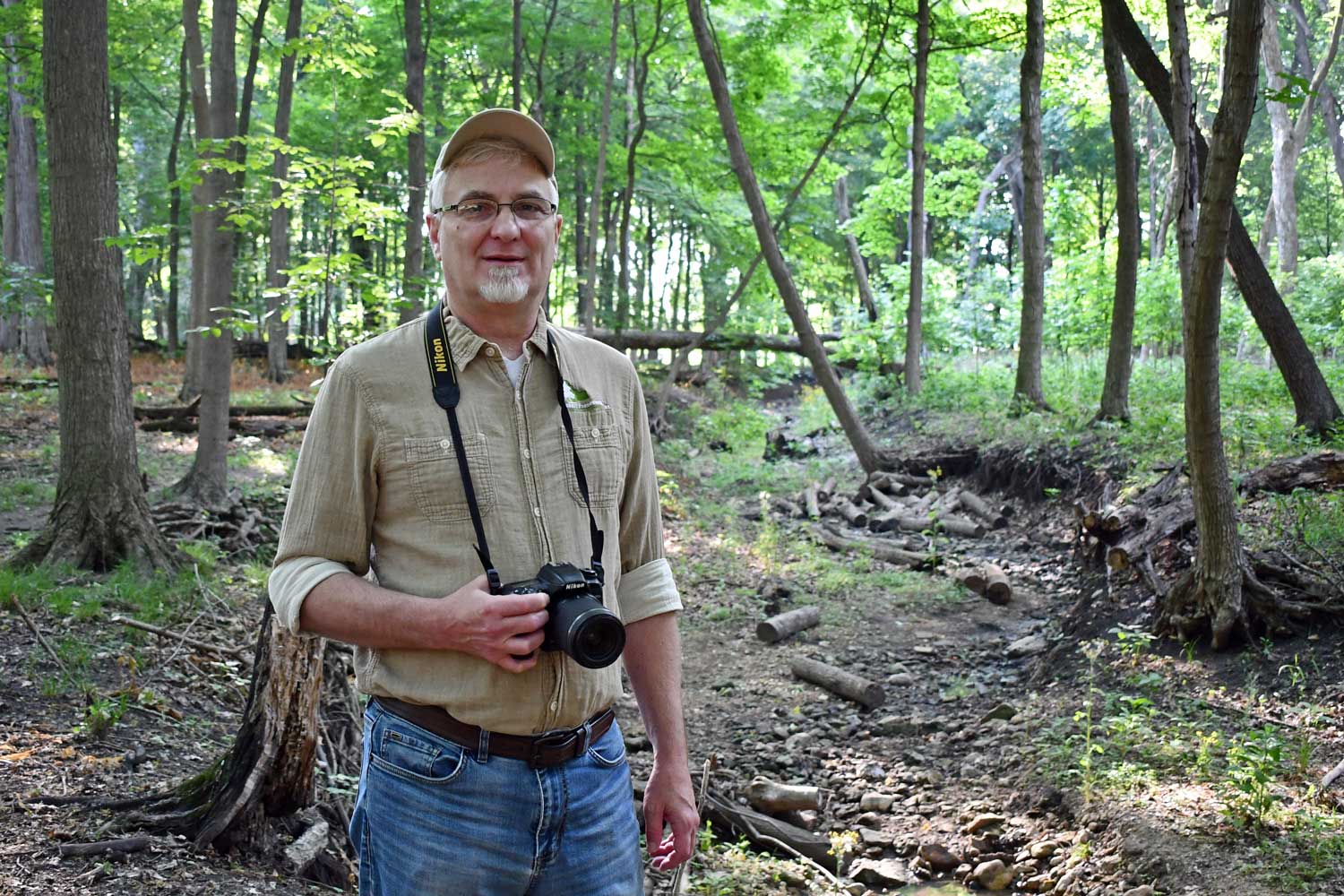 A person standing in a forest with a camera.