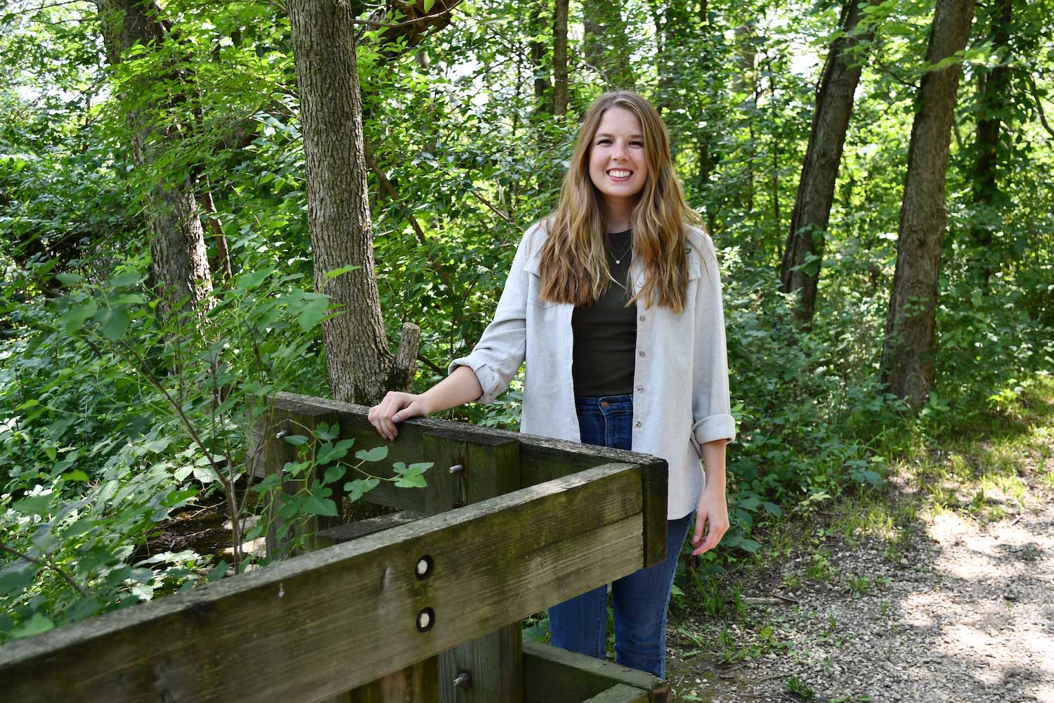 A person standing next to a bridge on a trail.