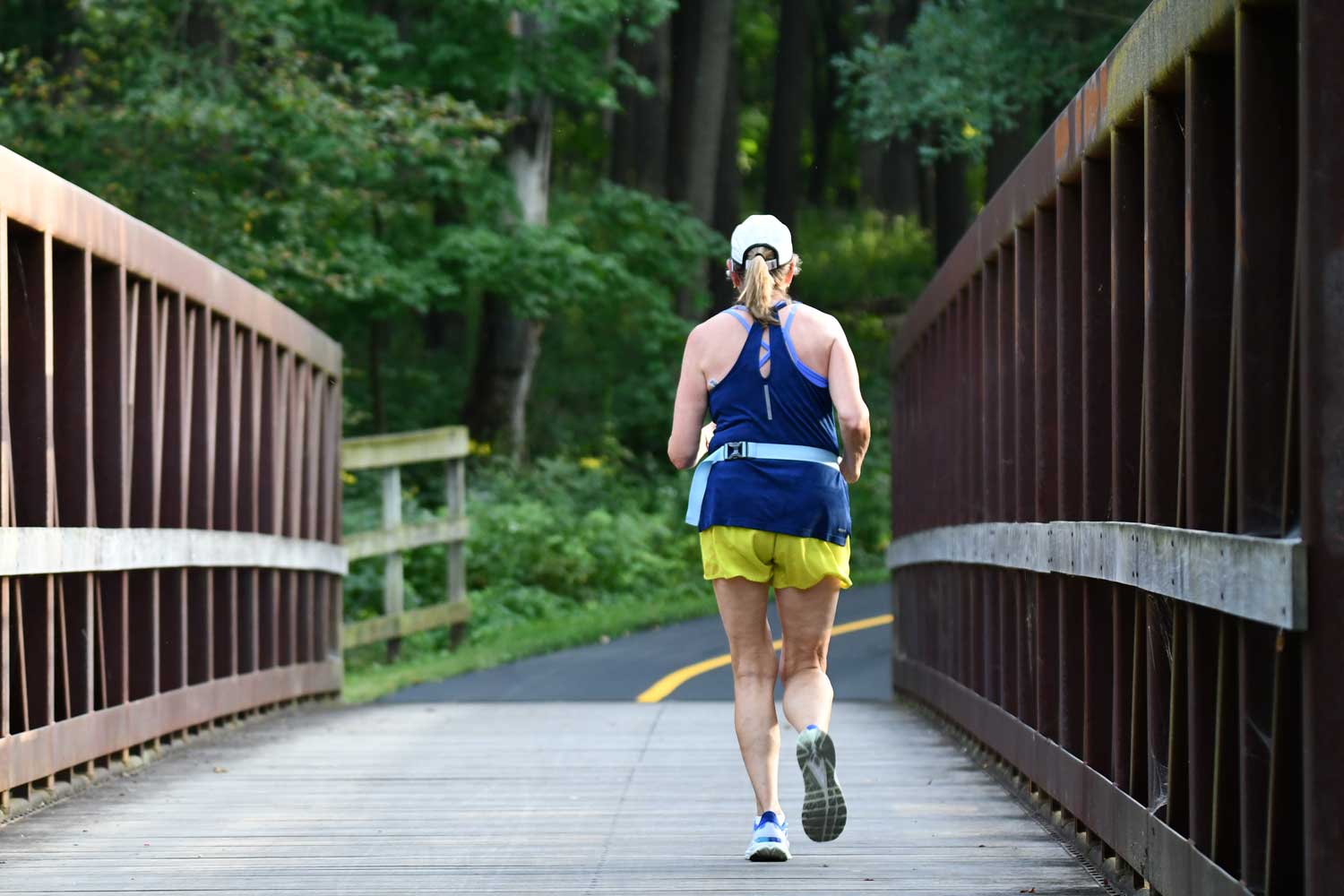 Person running over a bridge along a trail.