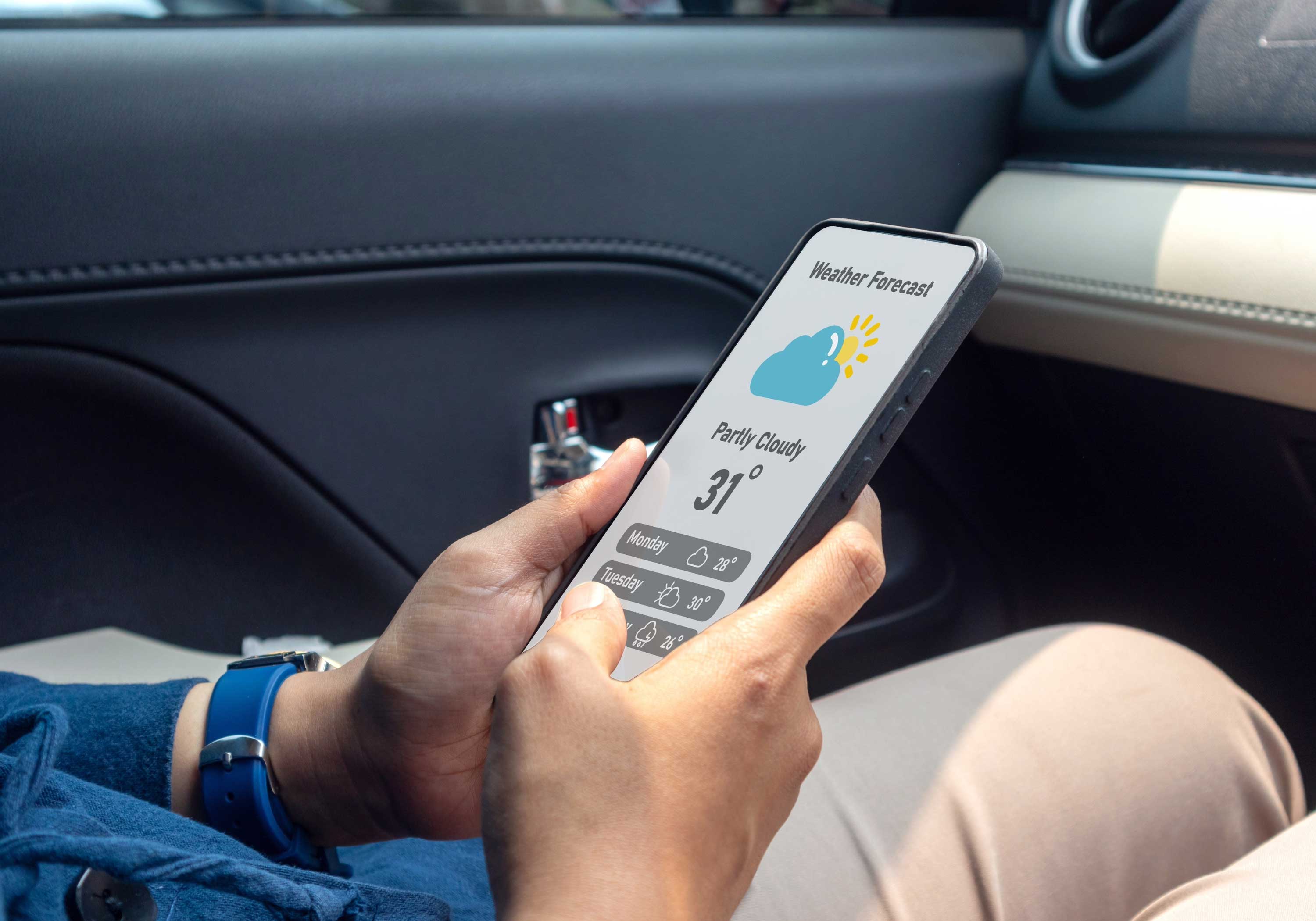 Person checking the weather forecast on a smartphone while sitting in a car.