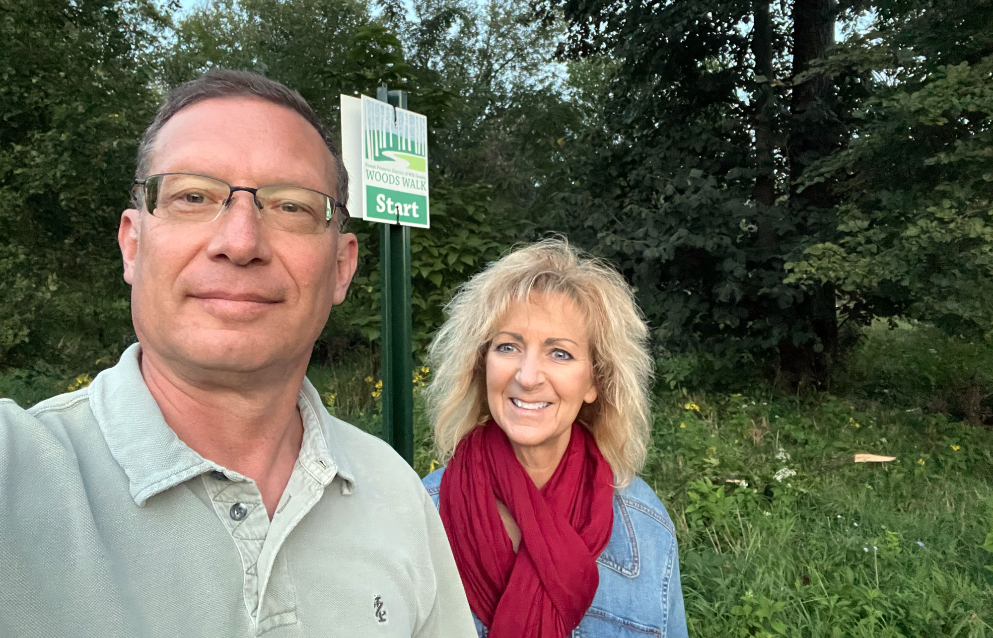 A man and woman take a selfie along a trail.