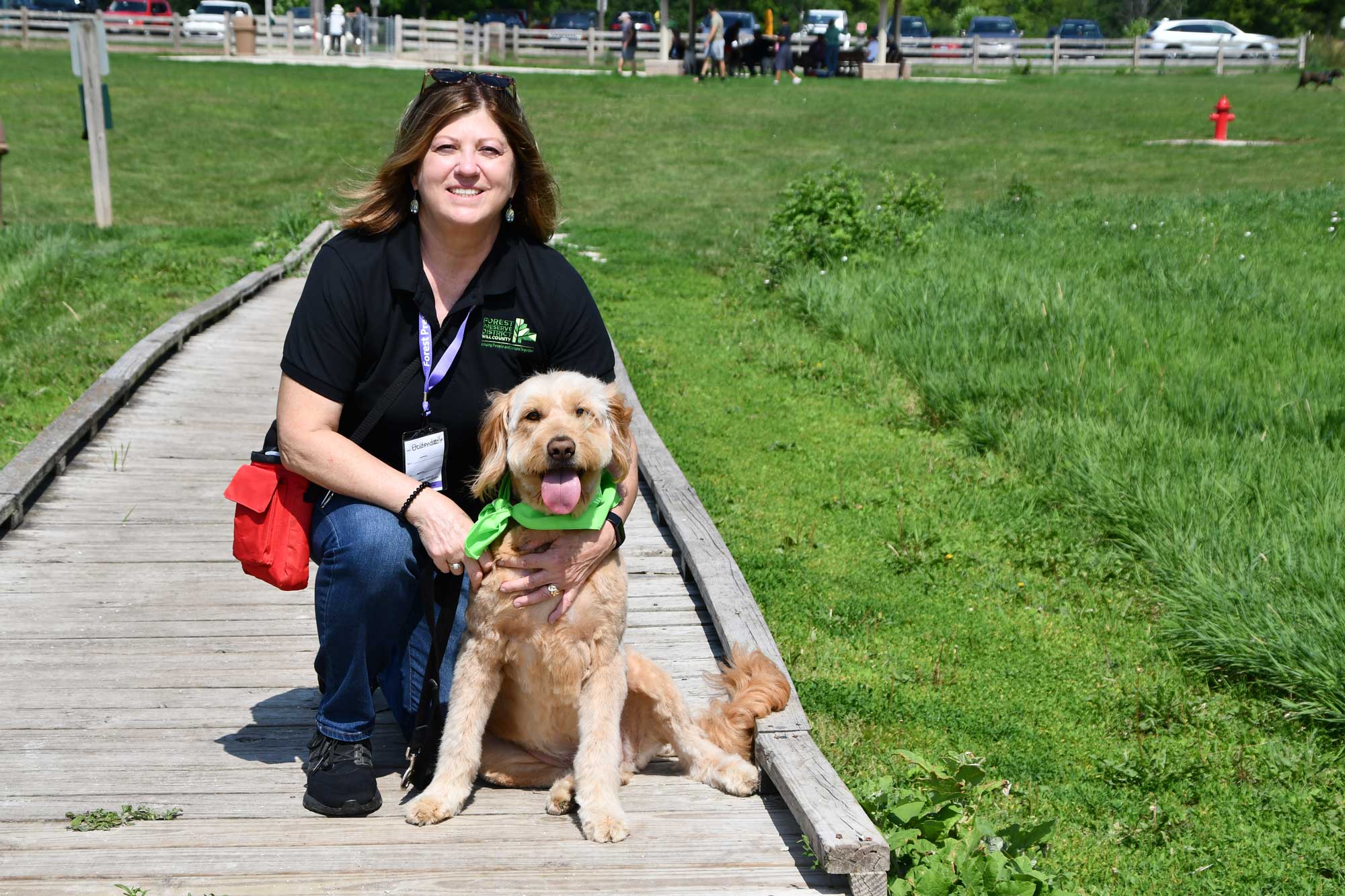 A woman poses with her dog at a park.