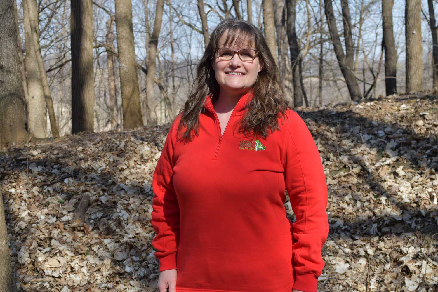 A person posing for a photo with a forest as the backdrop.