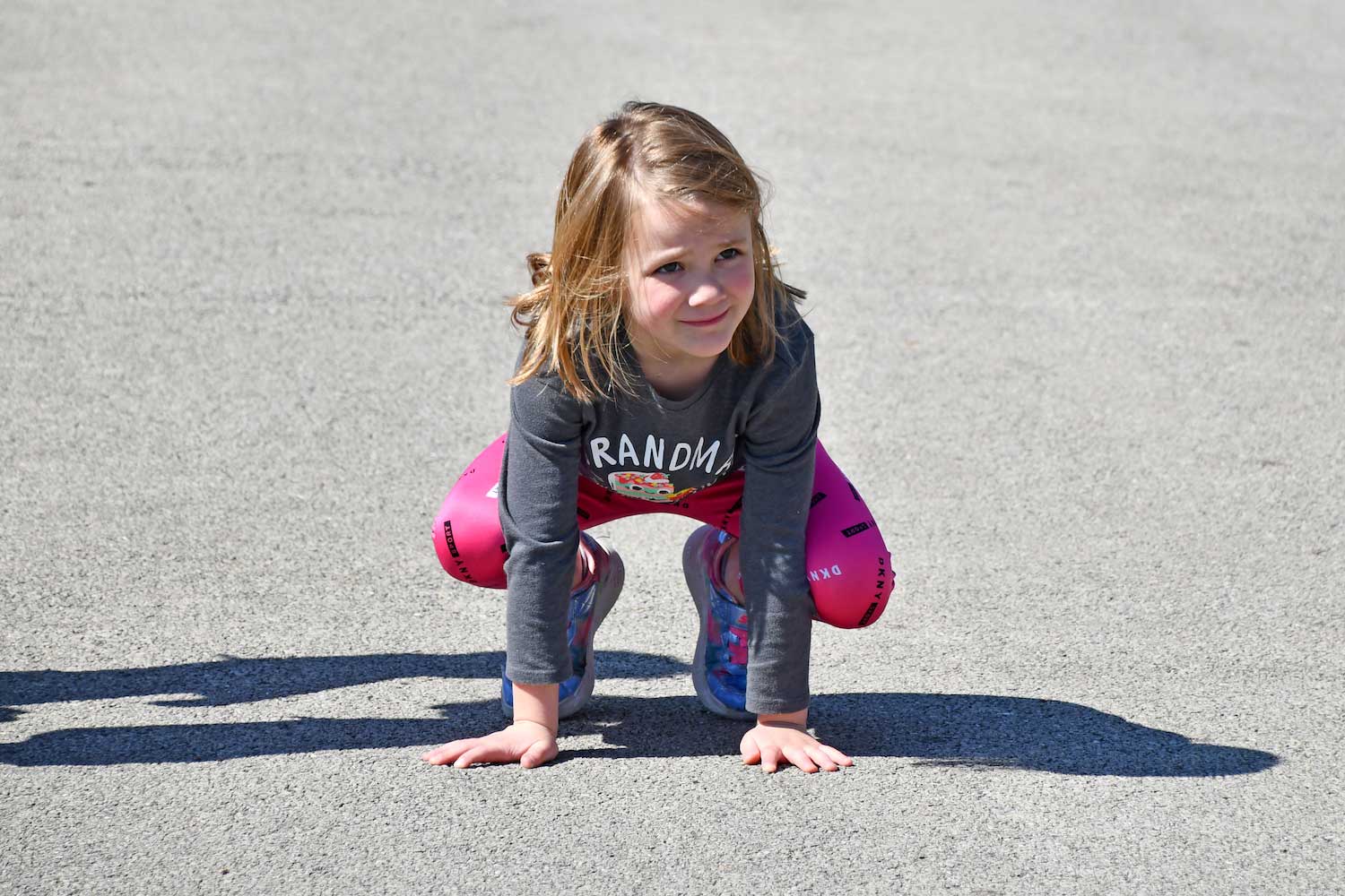 A girl leapfrogging on the ground.