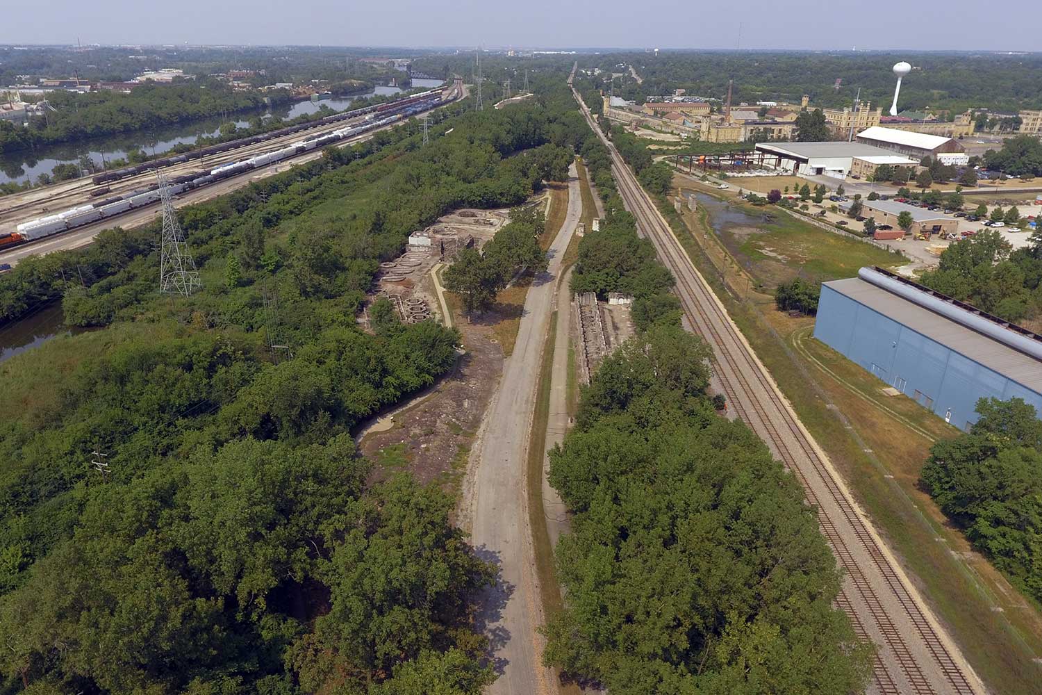 An aerial view of railroad tracks and a road running alongside the remains of an old steel mill.