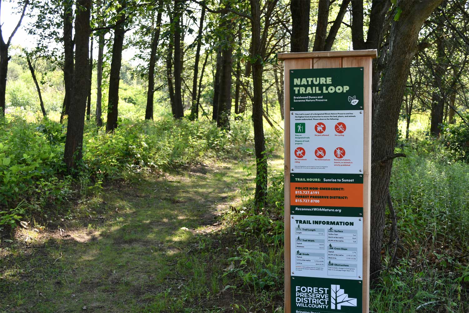 Trail sign in front of a grass trail.